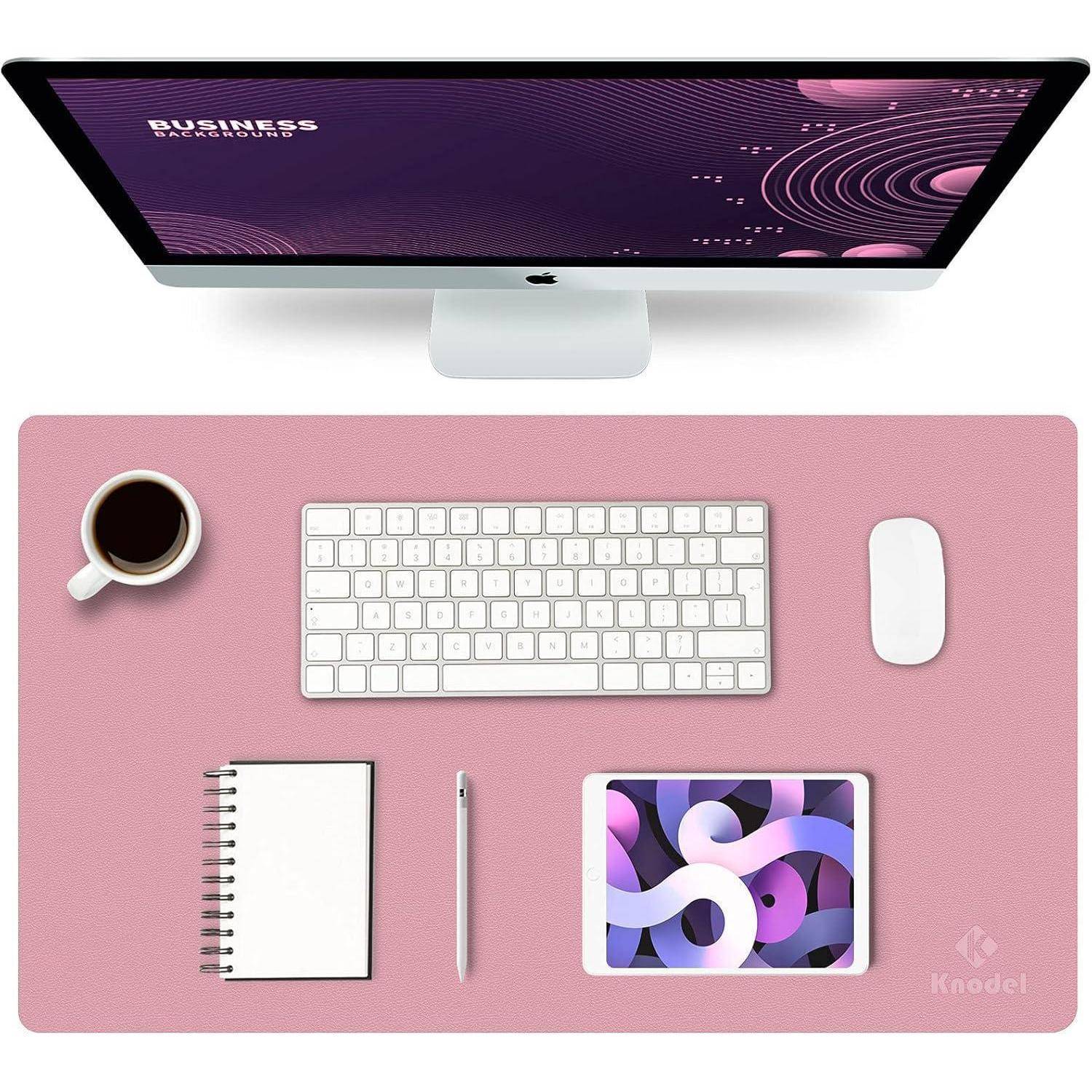 Ein Computer mit einer Geschäftspräsentation auf dem Bildschirm, begleitet von einer Tastatur, Maus, Kaffee, Notizbuch, Stift und Tablet auf einem rosa Schreibunterlage.
