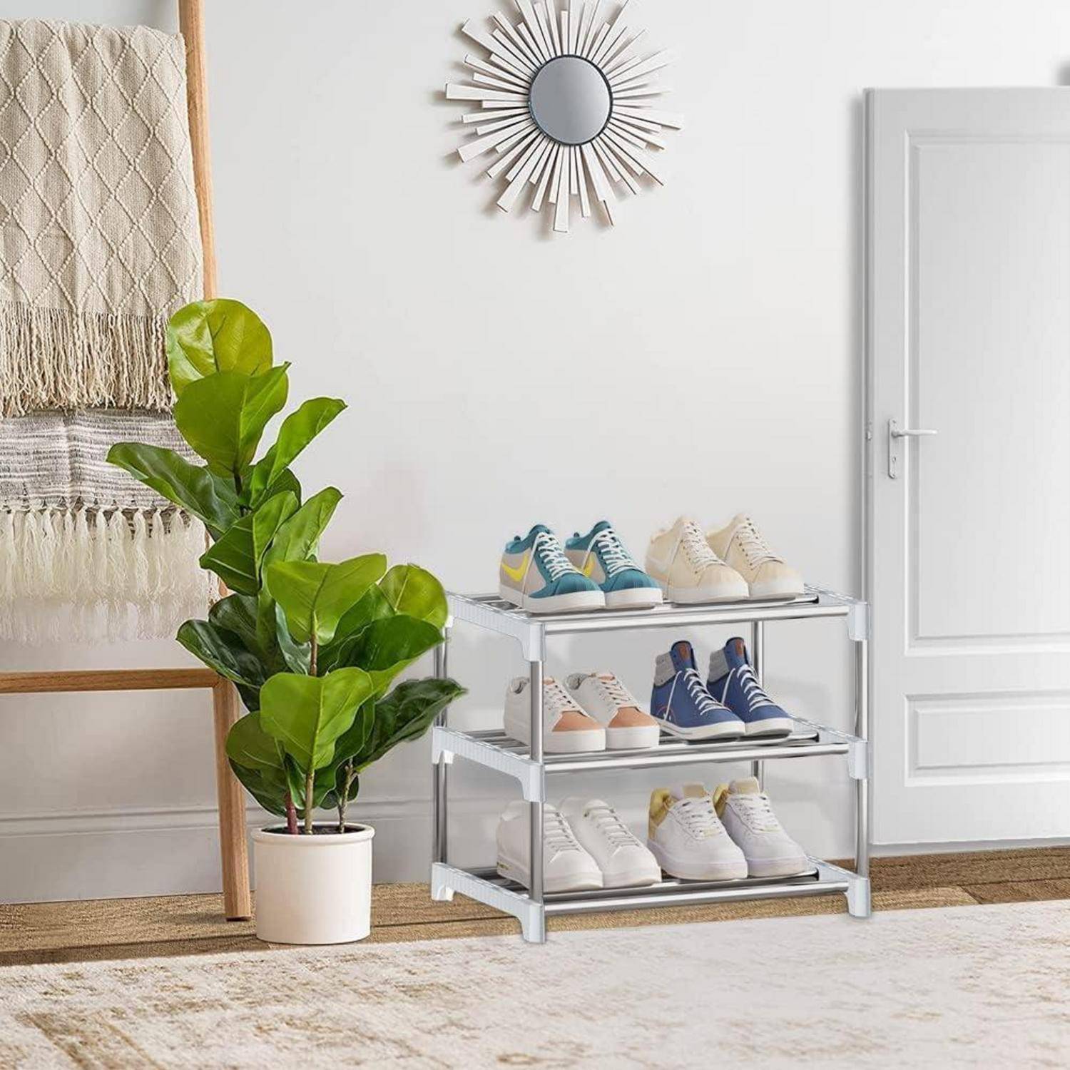 Ein ordentlich angeordnetes Schuhregal mit drei Regalen voller Schuhe steht neben einer Topfpflanze und einem strukturierten Wandbehang in einem hellen, minimalistischen Raum.
