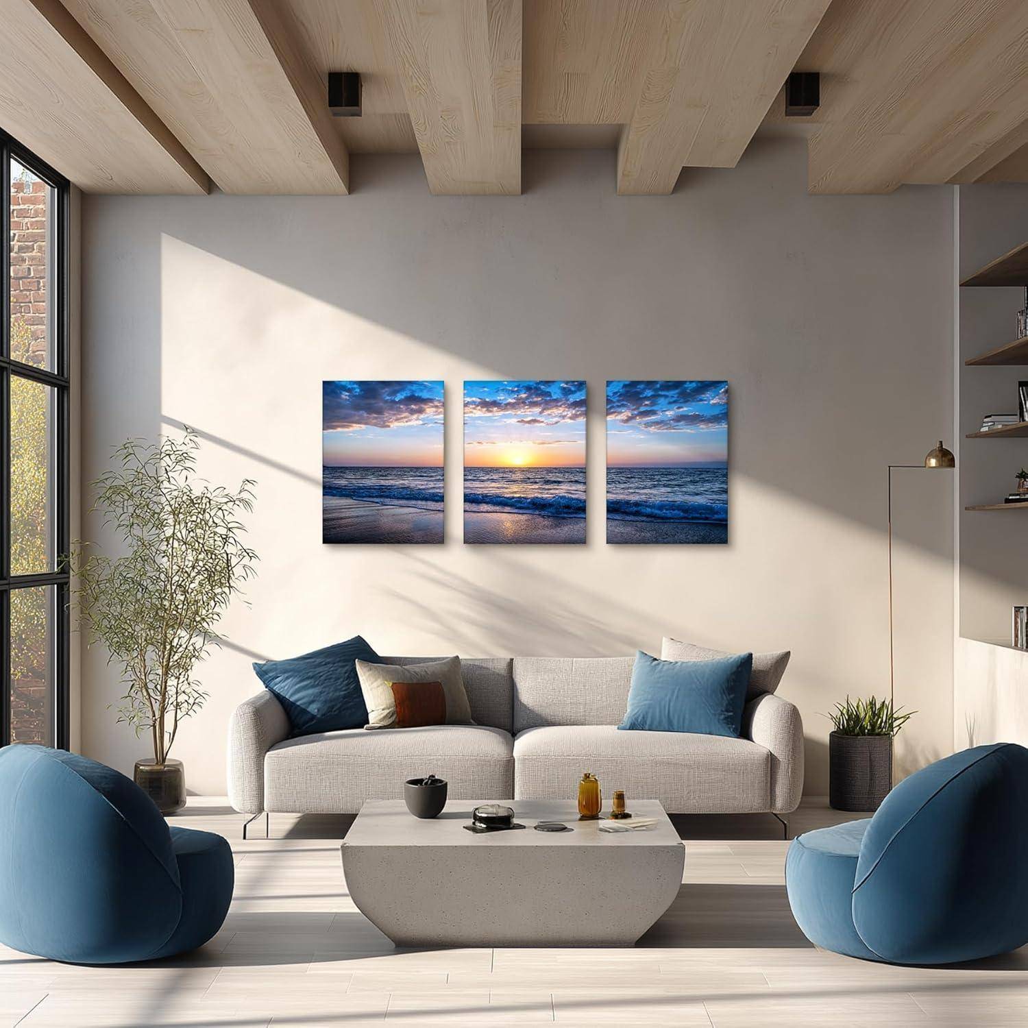 Ein modernes Wohnzimmer mit einem grauen Sofa, blauen Sesseln, einem Couchtisch und einem Kunstwerk, das einen Sonnenuntergang über dem Ozean an der Wand zeigt.