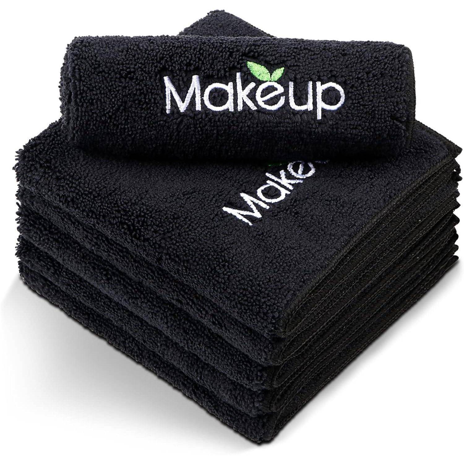 Ein Stapel schwarzer Handtücher, bestickt mit der Aufschrift 'Makeup' und einem grünen Blattmotiv.