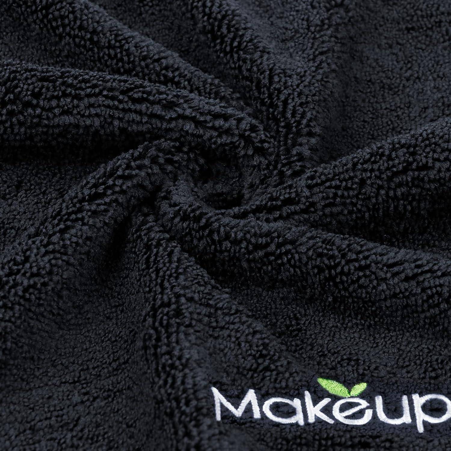 Eine Nahaufnahme von weichem, schwarzem strukturiertem Stoff mit dem Wort 'Makeup' und einem grünen Blatt-Logo in der Ecke.