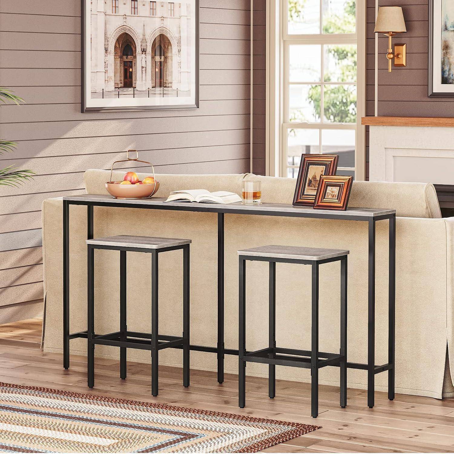 Ein gemütliches Wohnzimmer mit einem beigen Sofa, einem Holzcouchtisch und Barhockern. Sonnenlicht strömt durch ein großes Fenster. Ein Bild hängt an der Wand.