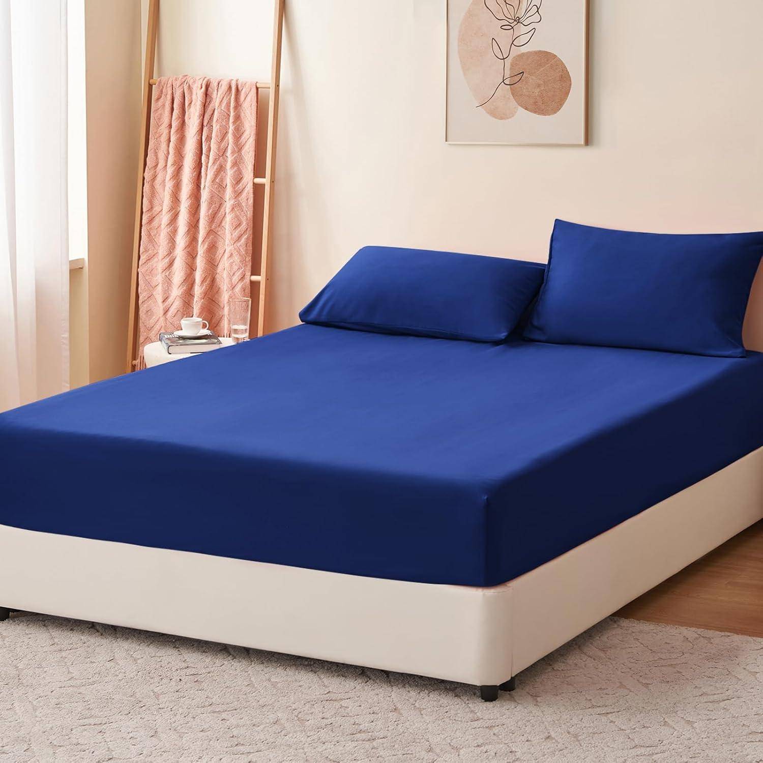 Ein sorgfältig gemachtes Bett mit einem tiefen blauen Spannbettlaken und Kissen in einem sanft beleuchteten Raum, mit einer hohen Leiter, auf der eine rosa Decke liegt, und minimalistischer Einrichtung.