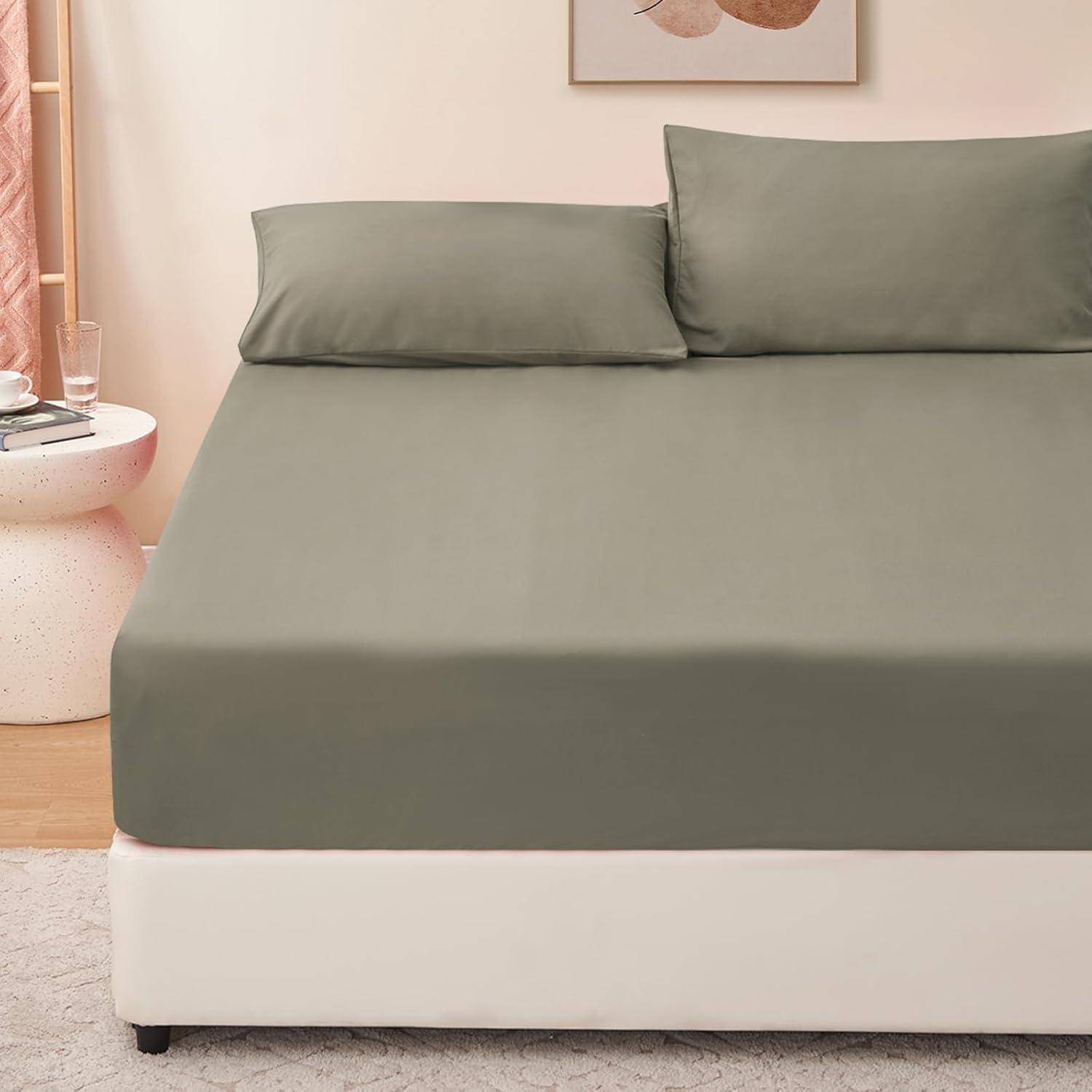 Ein ordentlich gemachtes Bett mit dunkelgrünen Laken und Kissen in einem sanft beleuchteten Schlafzimmer. Ein runder Beistelltisch mit einem Glas und einem Buch steht in der Nähe.