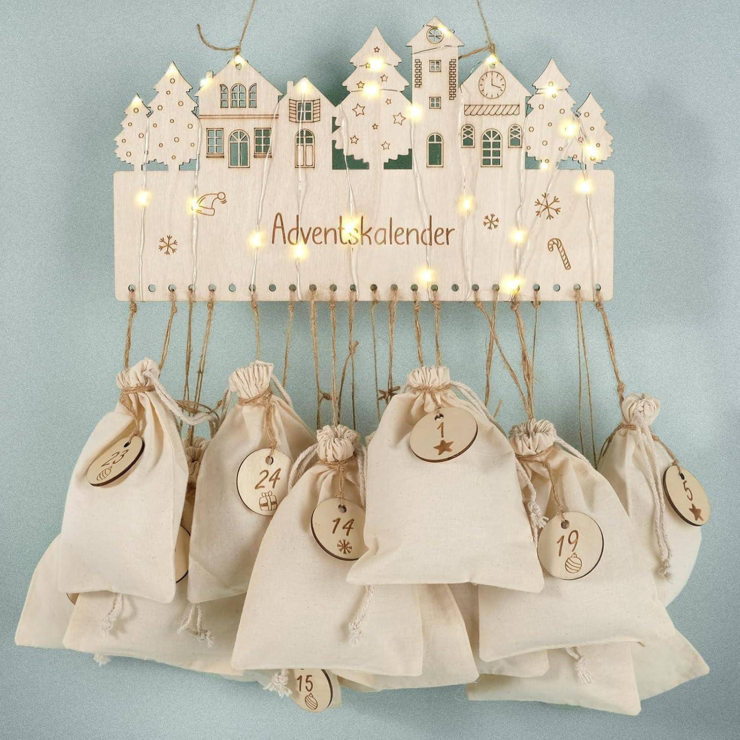 Holz-Adventskalender mit Leinenbeuteln zum Aufhängen, nummeriert von 1 bis 24, mit einer festlichen Dorfszene und kleinen Lichtern darüber.
