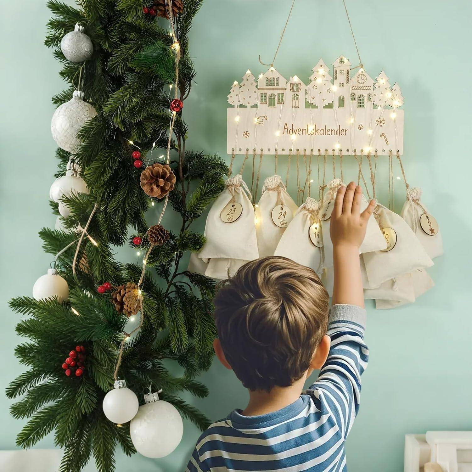Ein Kind greift nach einem nummerierten Beutel an einem Adventskalender, der mit Tannenzweigen und Ornamenten geschmückt ist und den Countdown bis Weihnachten markiert.
