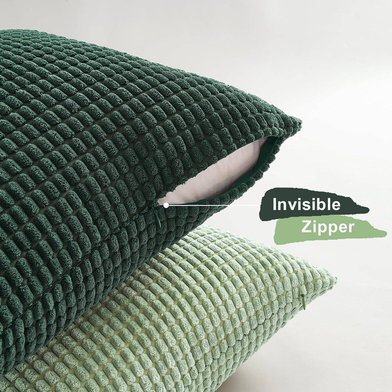 Ein dunkelgrünes strukturiertes Kissen mit einem 'Invisible Zipper'-Etikett liegt auf einem hellgrünen Kissen und zeigt dabei das Reißverschluss-Detail.