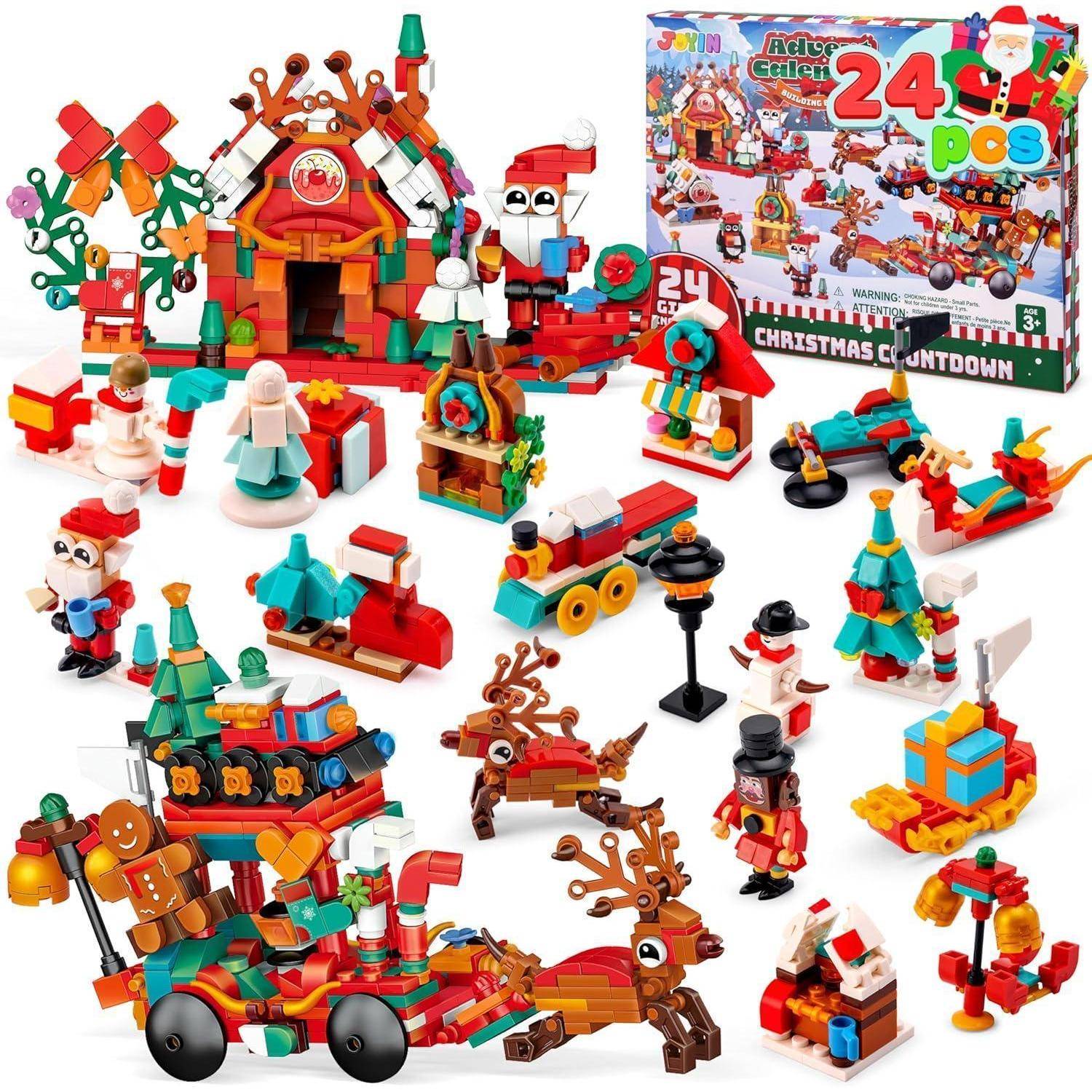 Eine Sammlung bunter Weihnachts-Bauklötze mit Figuren, Geschenken, Rentieren, Santa und einem Spielzeugzug in der Nähe einer Schachtel.