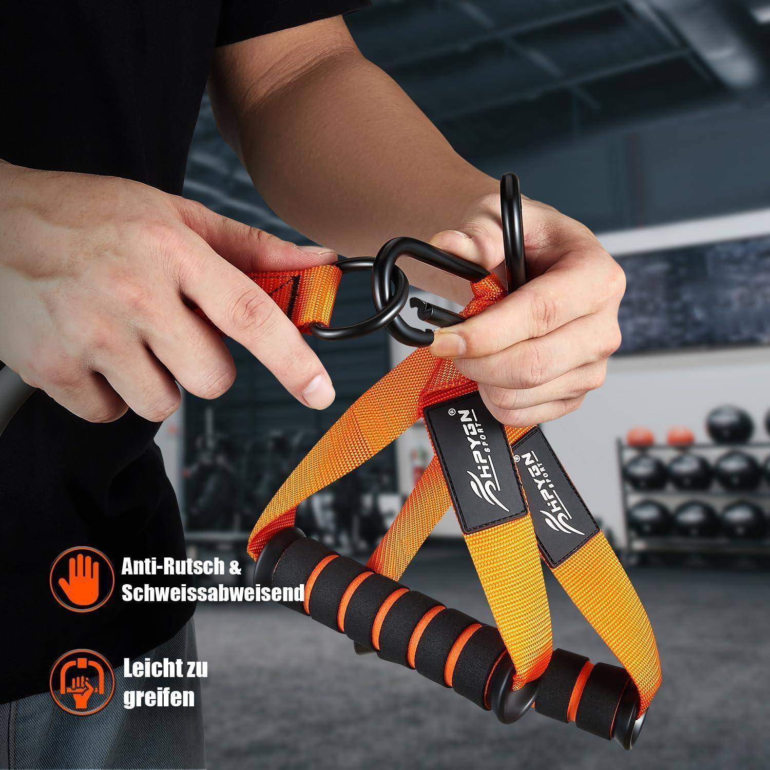 Eine Person hält ein orangefarbenes Übungsband mit schwarzen Griffen in einem Fitnessstudio. Das Band trägt die Aufschrift 