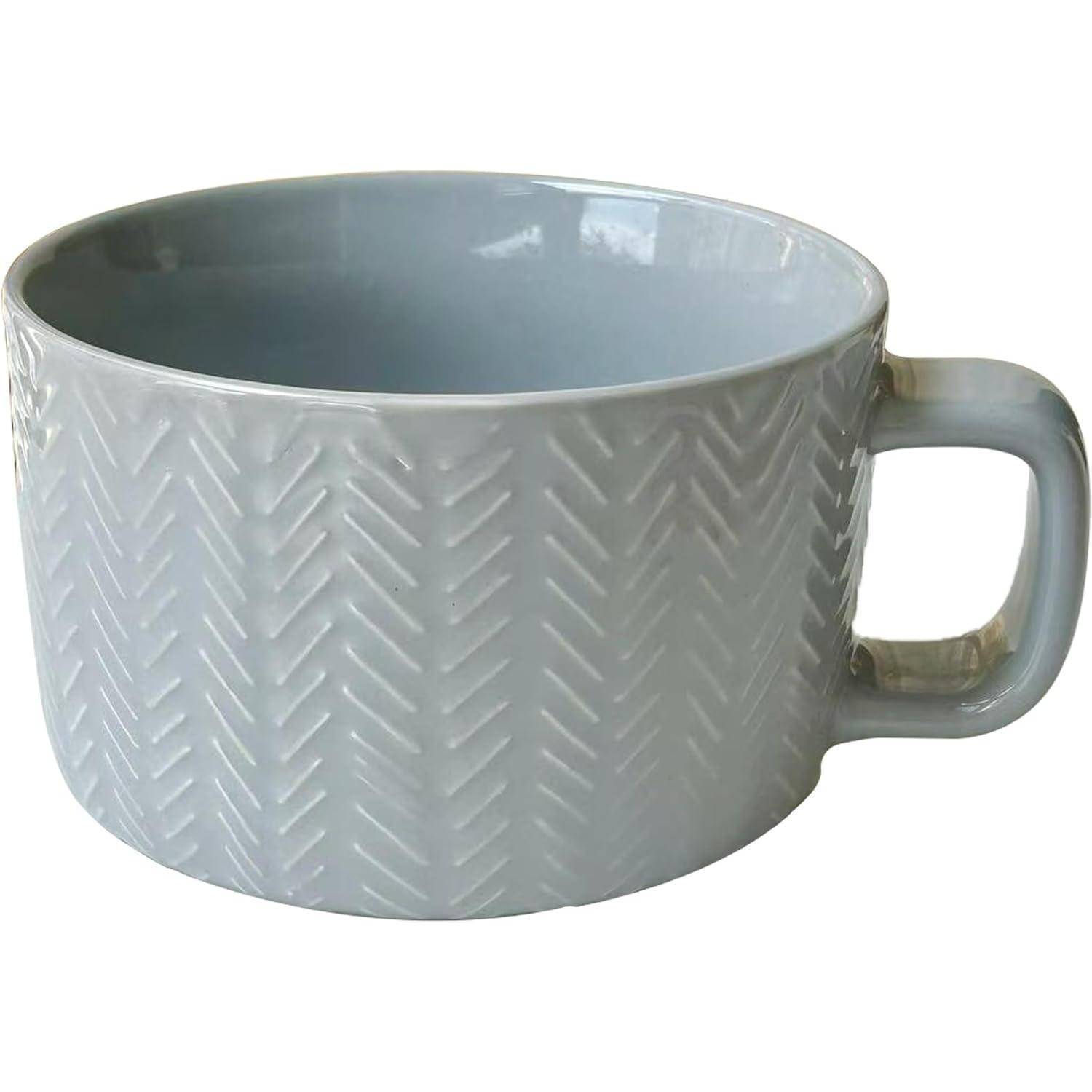 Eine weiße Keramiktasse mit einem strukturierten Zickzackmuster auf der Außenseite, mit einem Henkel auf der rechten Seite.