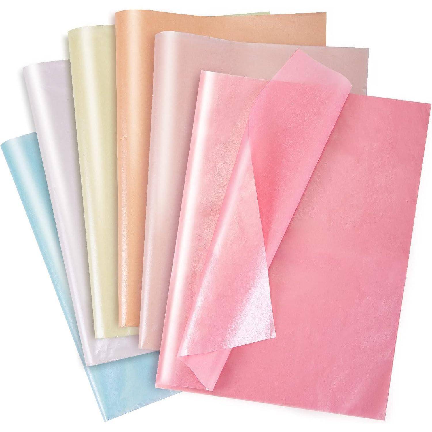 Mehrere Blätter Seidenpapier in Pastellfarben, darunter Rosa, Pfirsich, Gelb und Blau, überlappen sich in einer Fächeranordnung.
