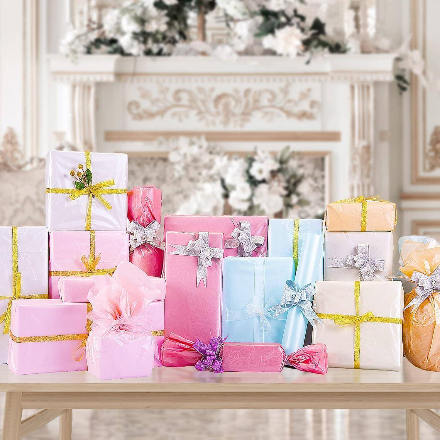 Eine Sammlung pastellfarbener Geschenkboxen mit Bändern, die auf einem Tisch in einem üppig dekorierten Raum mit Blumen- und ornamentaler Dekoration angeordnet sind.