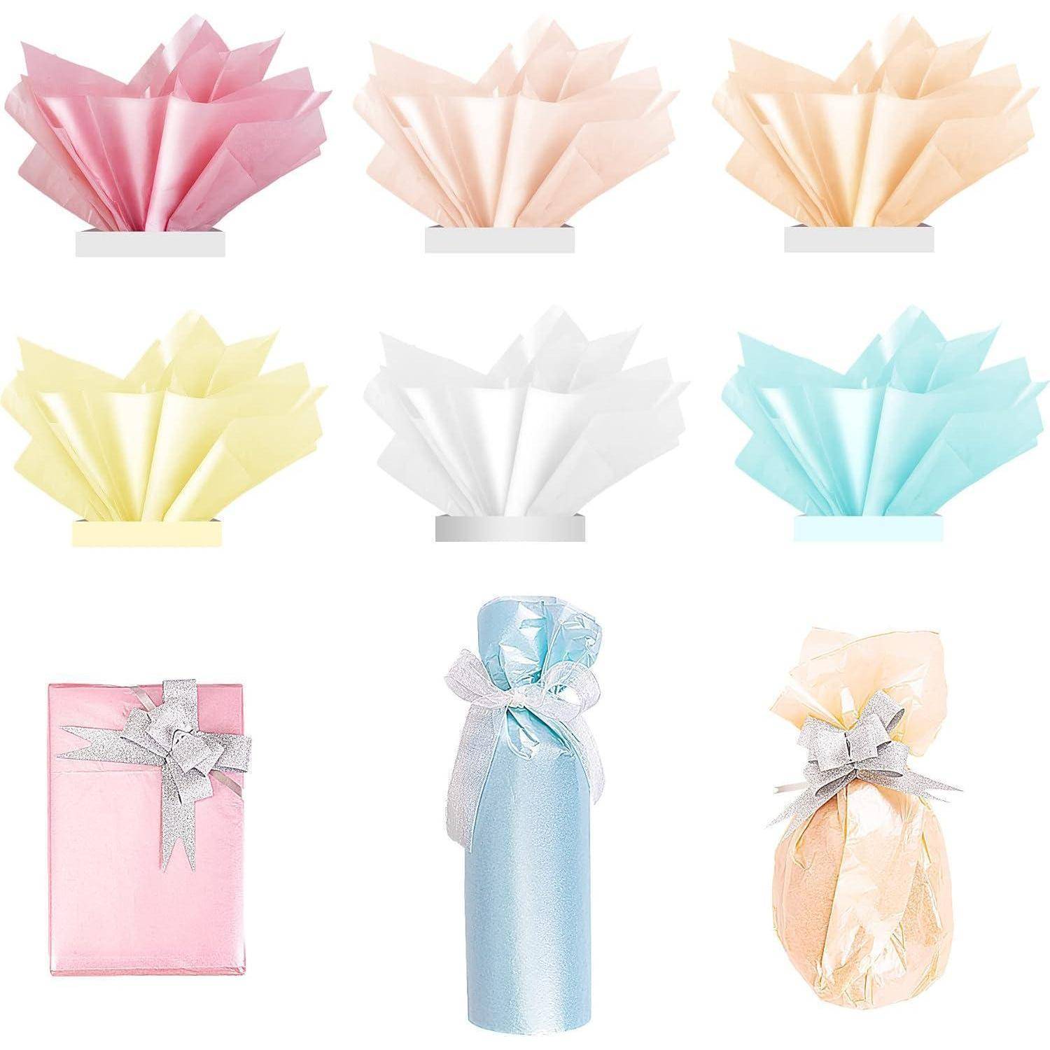 Geschenkverpackungsideen mit Papier und Stoff: kunstvoll gefaltete Papierfächer in verschiedenen Pastellfarben und elegant eingepackte Flaschen und eine Schachtel.
