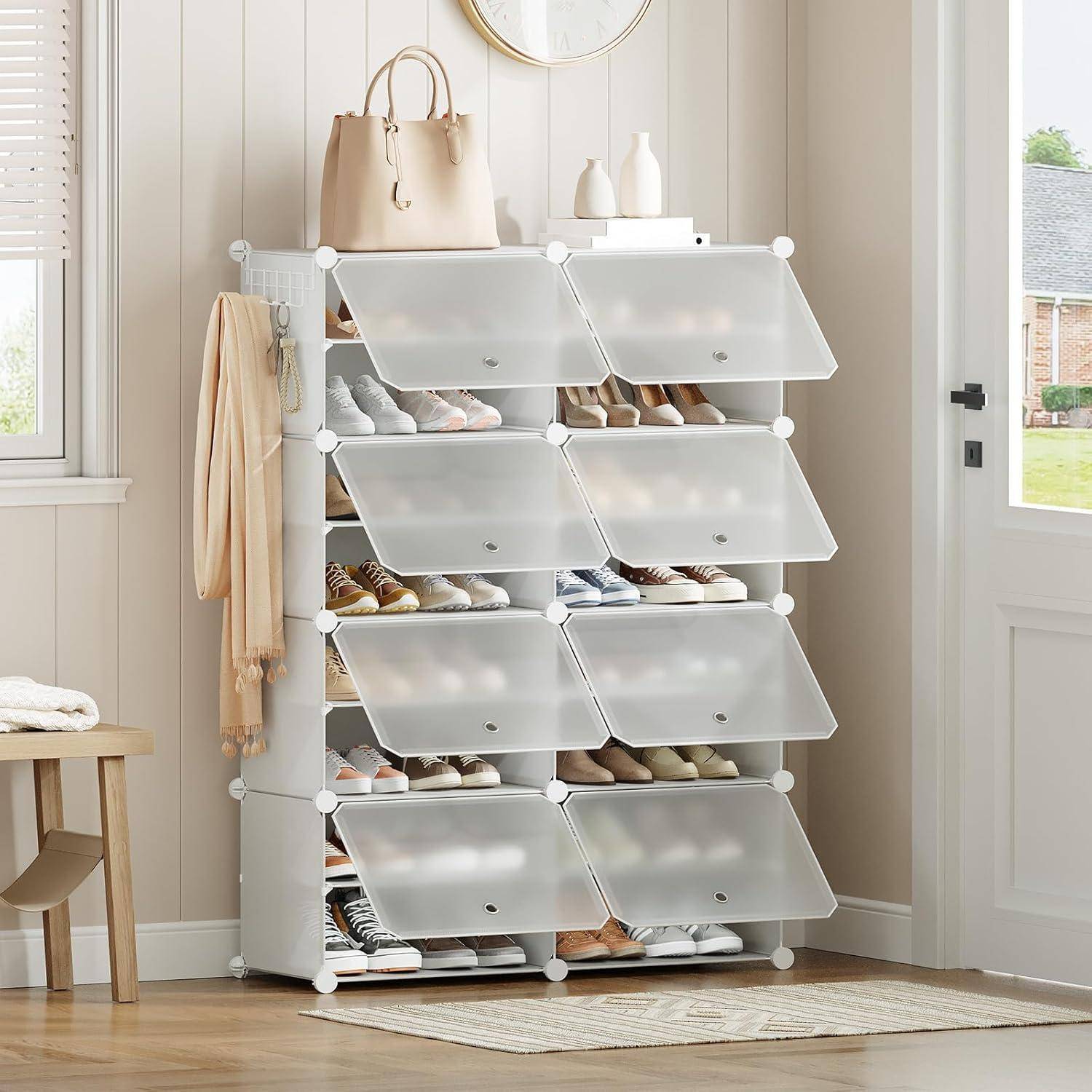 Ein weißer Schuhschrank mit transparenten Türen enthält verschiedene Paare von Schuhen. Eine Handtasche und Dekorationsgegenstände liegen oben darauf.