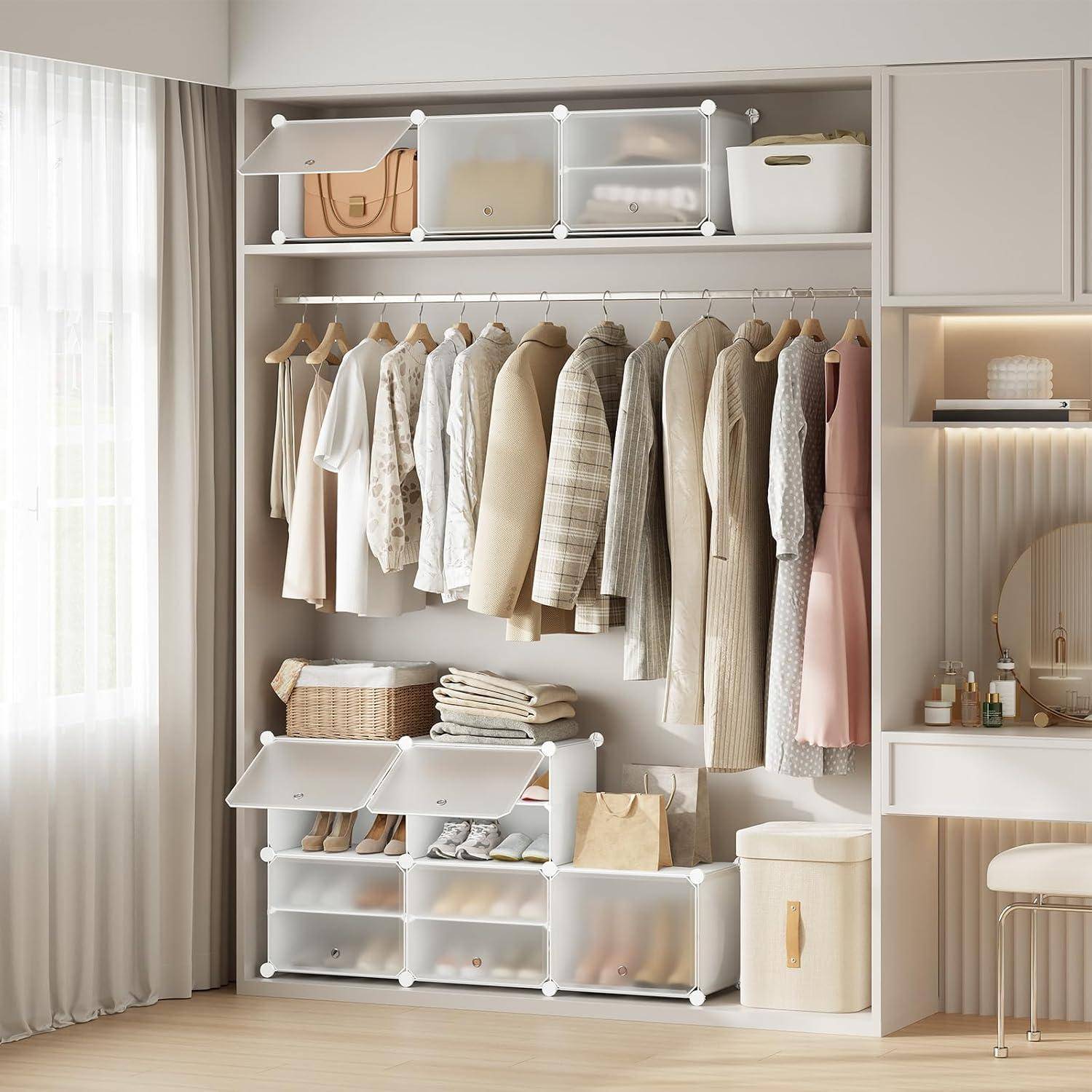 Übersichtlich geordneter Kleiderschrank mit Kleidungsstücken an Kleiderbügeln, Boxen auf den oberen und unteren Regalen und einer kleinen Kommode neben dem mit Vorhängen verhängten Fenster.