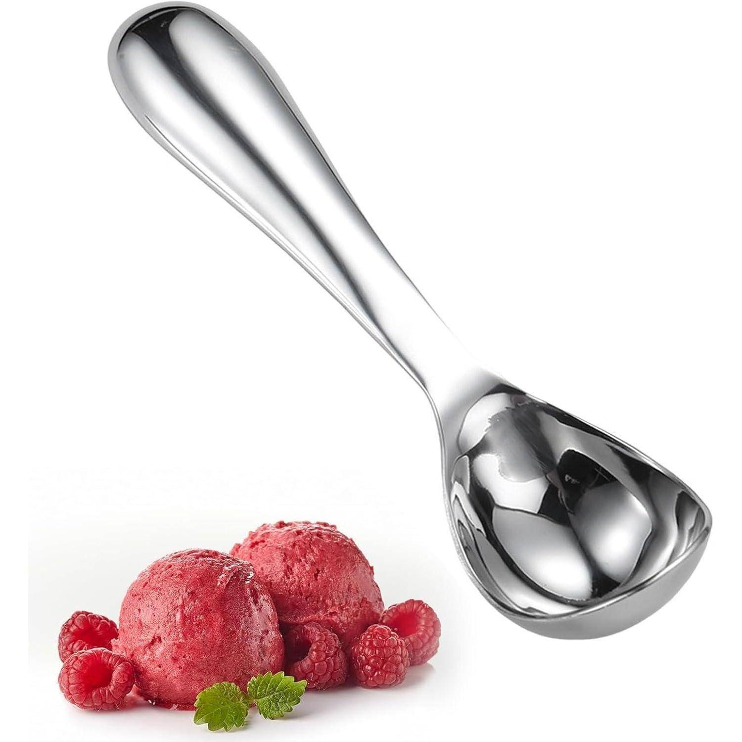 Ein silberner Eisspatel wird über zwei Himbeerkugeln Eis platziert und mit frischen Himbeeren und Minzblättern garniert.
