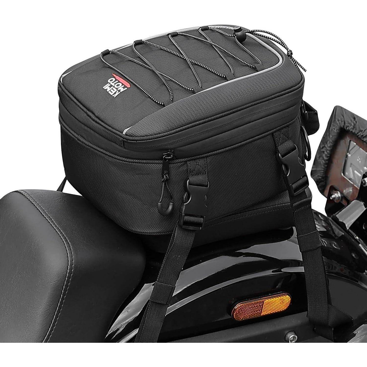 Eine schwarze Motorrad-Hecktasche mit Spanngurten und einem reflektierenden Logo ist auf einem Motorradsitz befestigt und zeigt ihre Ladekapazität.