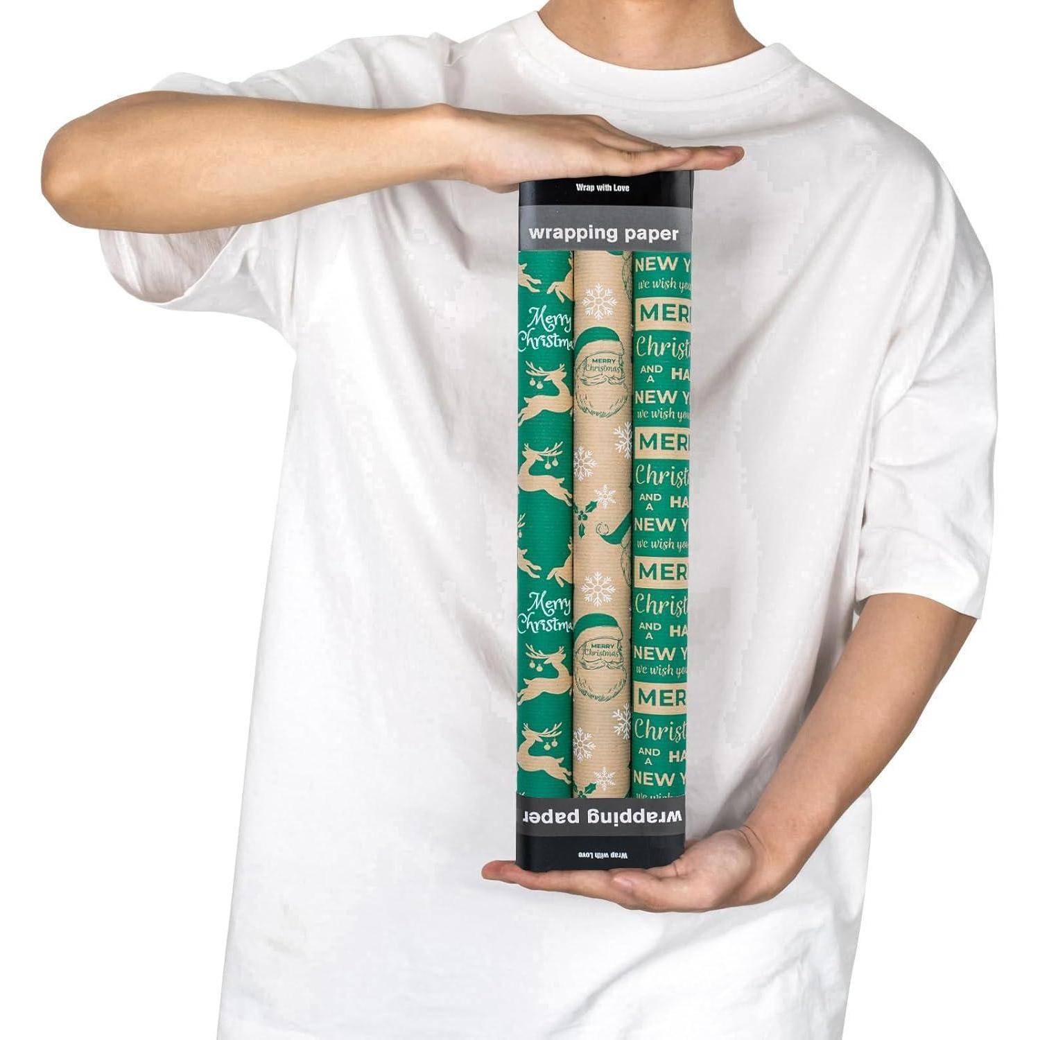Eine Person hält ein Paket mit drei Rollen Geschenkpapier im Weihnachtsmotiv mit Rentieren und festlichen Textdesigns.