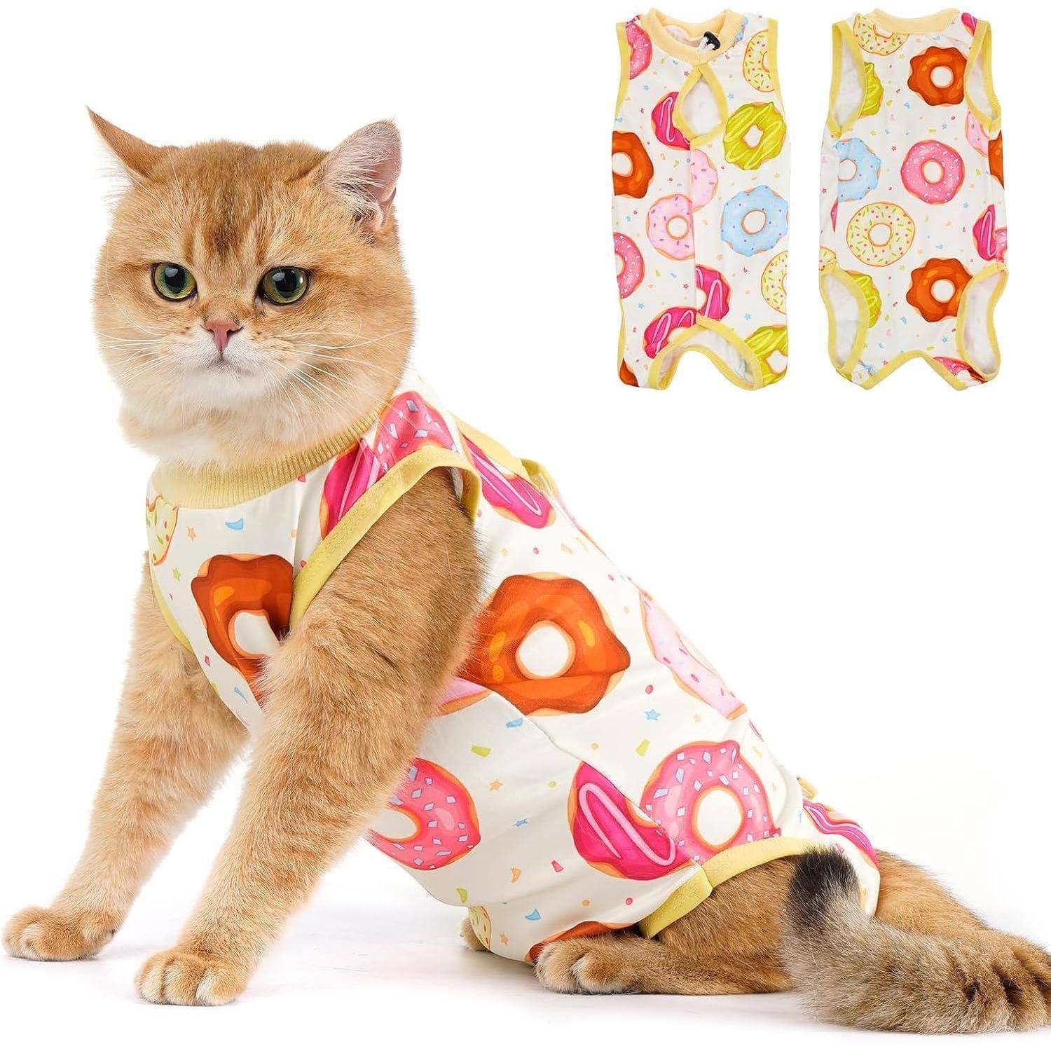 Eine Katze sitzt, die einen bunten Schlafanzug mit Donutmustern trägt, passend zu zwei ähnlichen Schlafanzügen im Hintergrund, einer in Gelb und der andere in gemischten Farben.