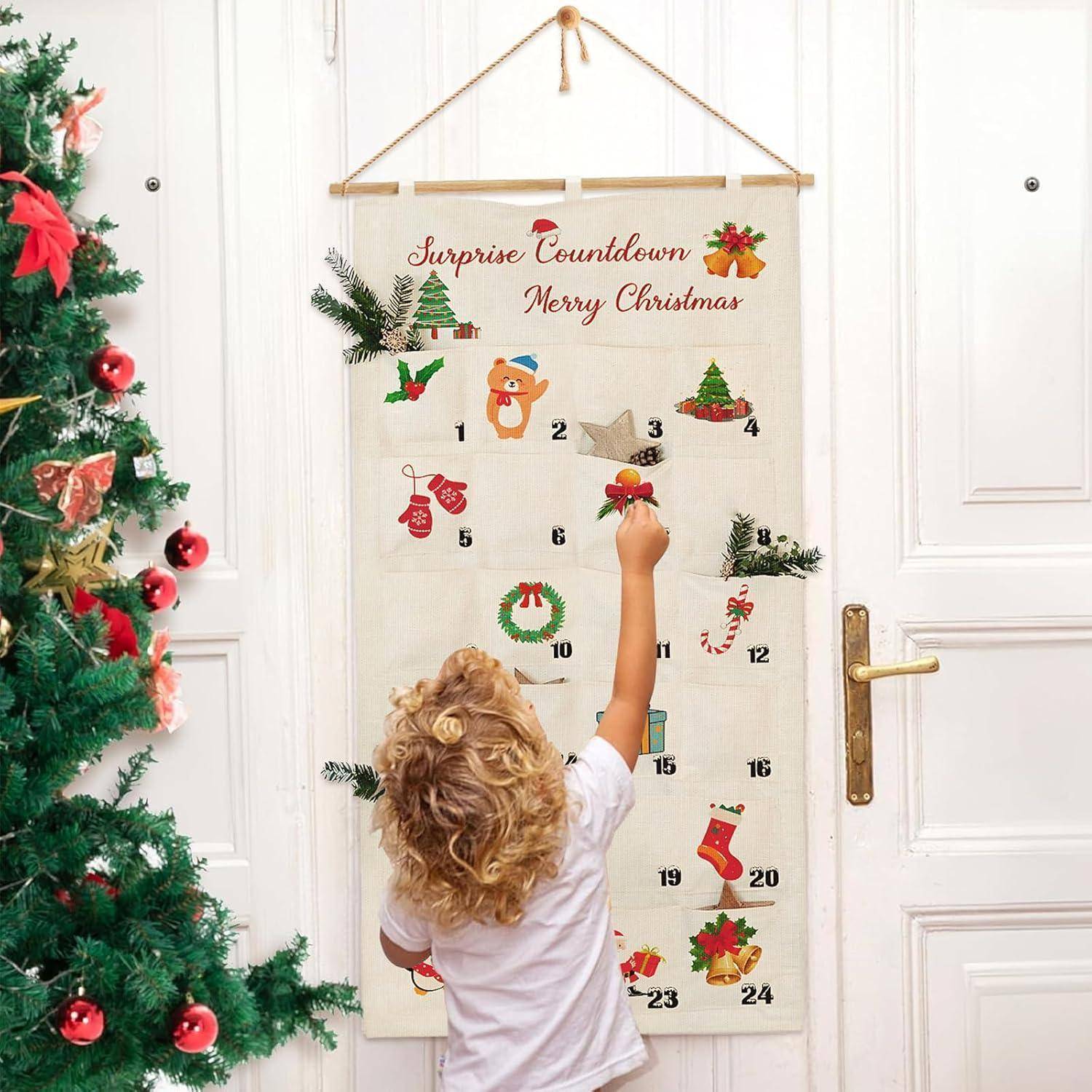 „Ein Kind hängt eine Dekoration an einen Adventskalender mit der Aufschrift ‚Überraschungs-Countdown Frohe Weihnachten' in der Nähe eines geschmückten Weihnachtsbaumes.