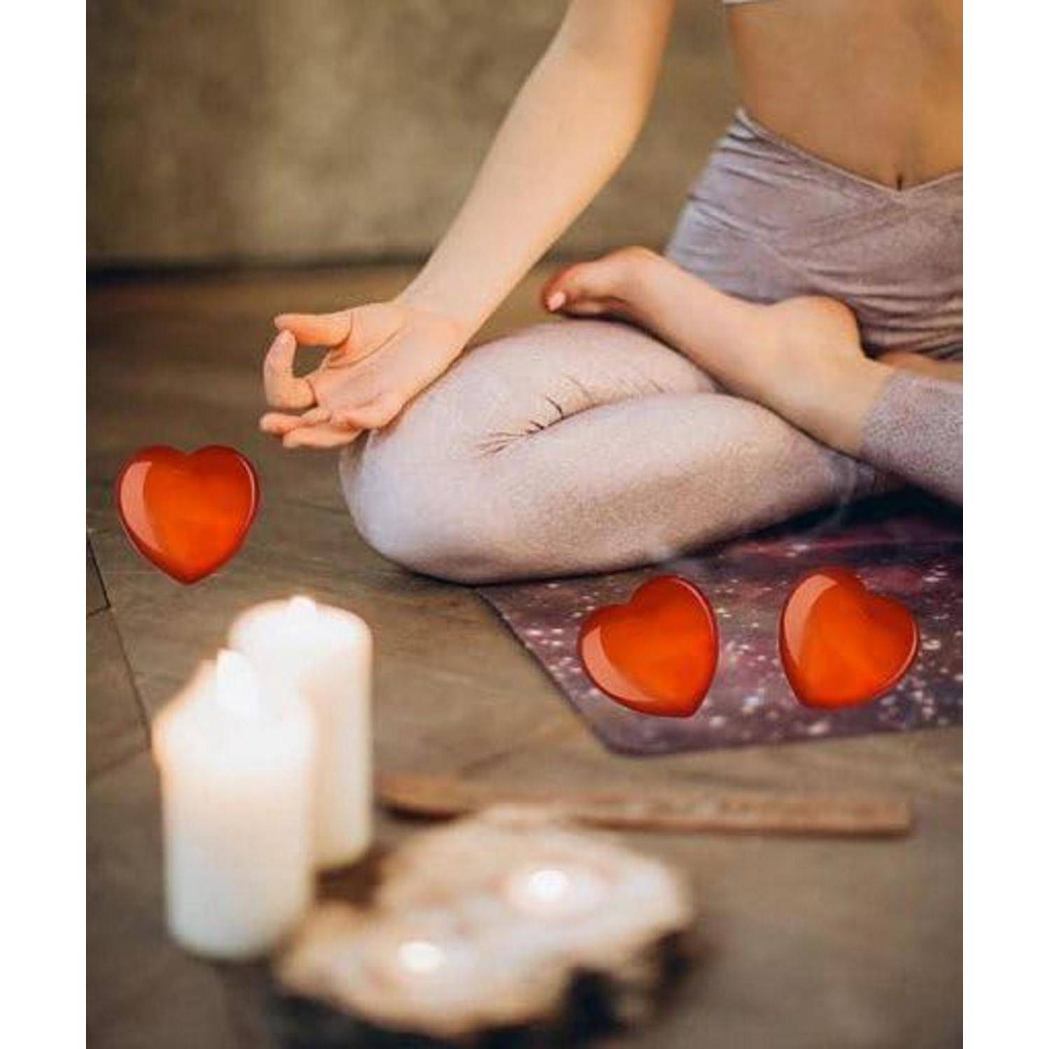 Eine Person in einer sitzenden Yogahaltung mit Kerzen im Vordergrund und drei schwebenden Herzen in der Nähe, die eine ruhige und beruhigende Atmosphäre schaffen.