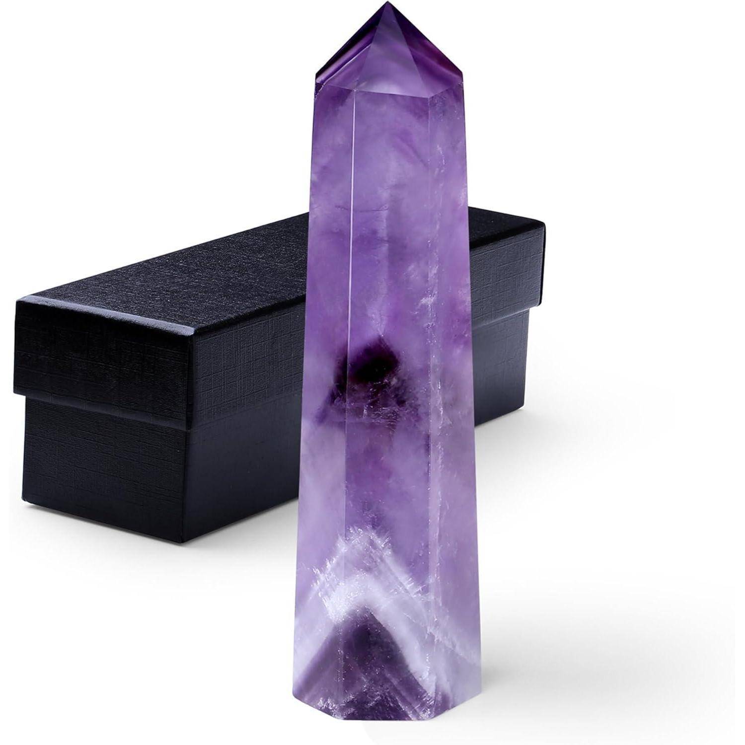Ein hoher, polierter violetter Kristallturm steht aufrecht neben einer schwarzen rechteckigen Schachtel und hebt dabei seine leuchtende Farbe und glatte Textur hervor.
