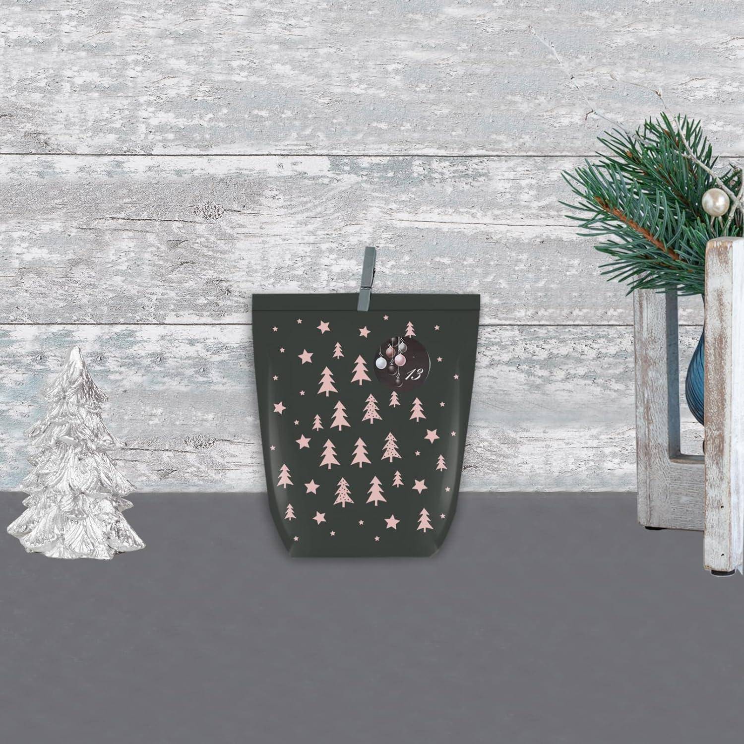 Eine dekorative Szene mit einem kleinen Weihnachtsbaum und einer hängenden dunkelgrünen Tasche mit rosa Baummustern und einer Weihnachtskugel vor einem rustikalen Holzhintergrund.