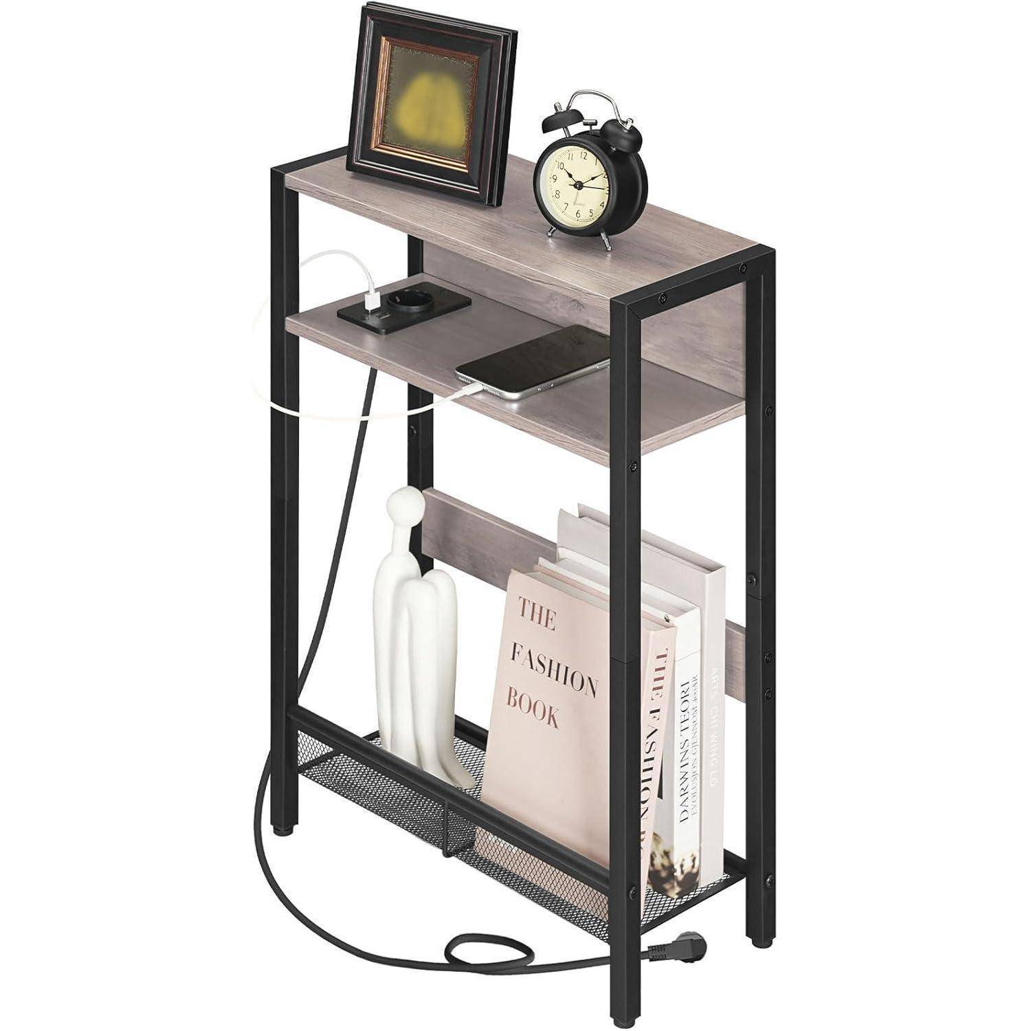 Ein kleines schwarzes Regal aus Metall und Holz trägt einen Fotorahmen, einen Wecker, ein Smartphone auf einer Ladestation und Bücher mit dem Titel 
