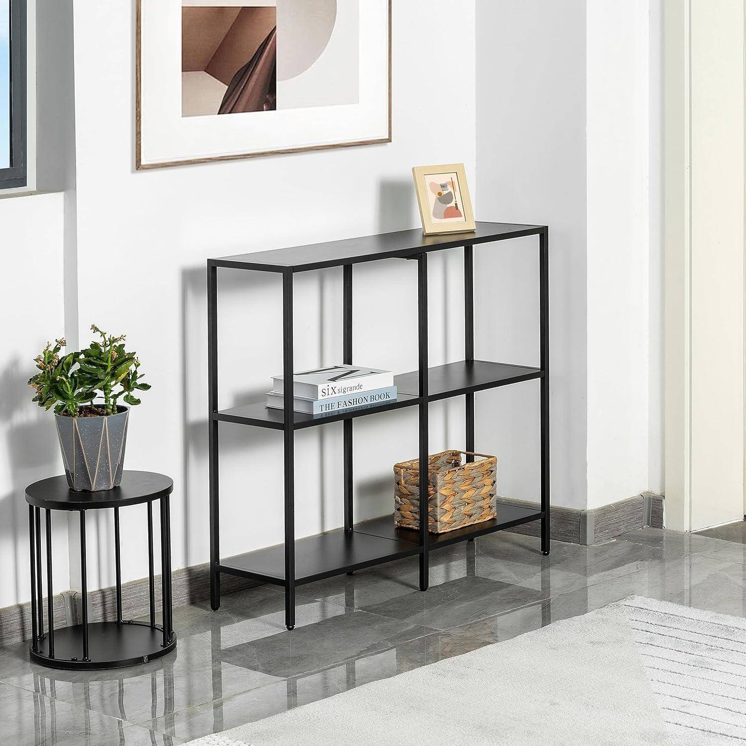 Ein minimalistischer Wohnraum mit einem schwarzen Metalltisch mit Konsole, vier Fächern, einem gerahmten Bild darüber, einer Pflanze auf einem runden Ständer und einem geflochtenen Korb.