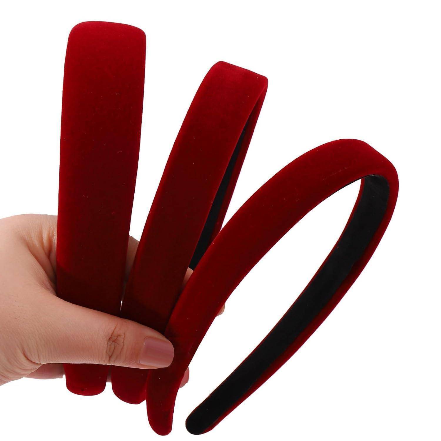 Eine Hand, die drei rote Samthaarbänder nebeneinander vor einem schlichten weißen Hintergrund hält.