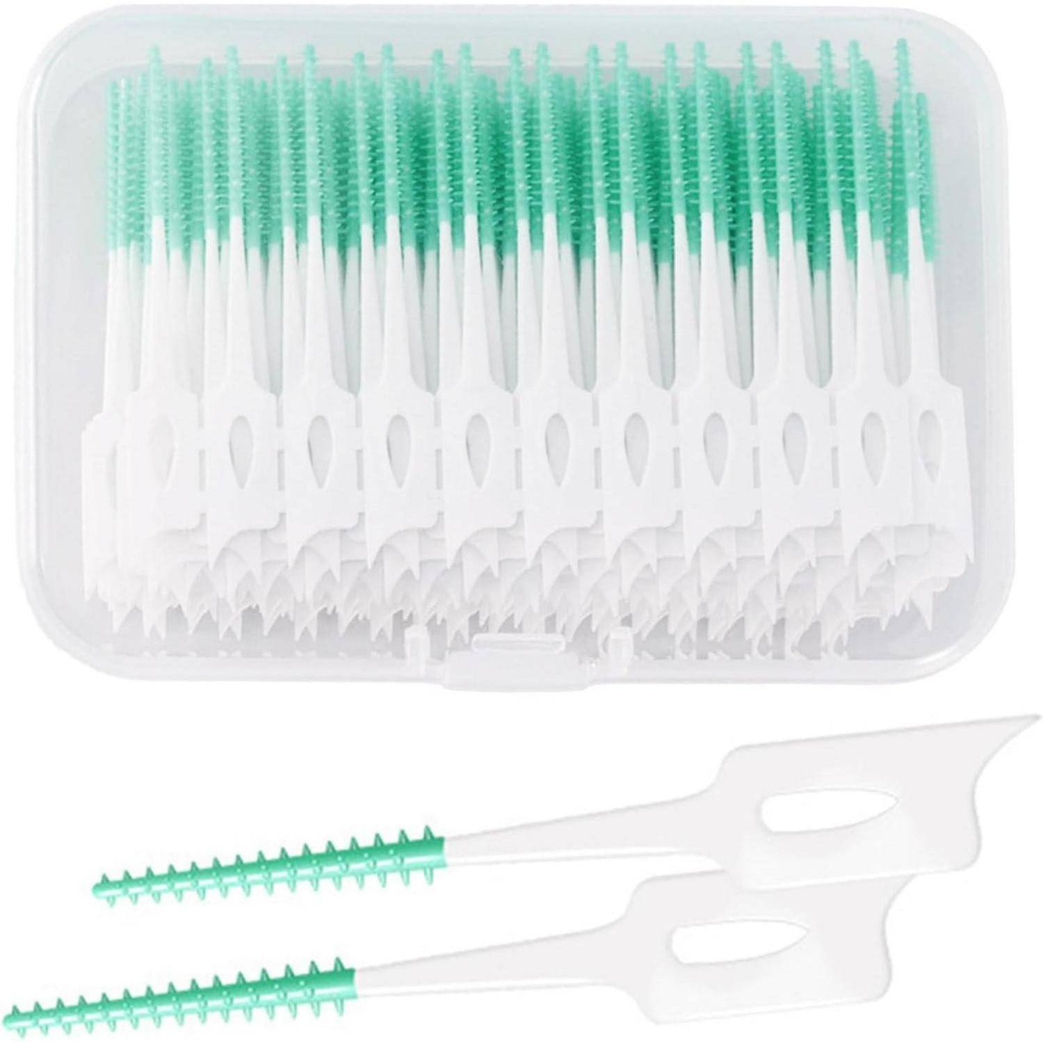 Eine durchsichtige Plastikbox mit mehreren grünen und weißen Zahnseidehaltern mit Borstenenden. Zwei Zahnseidehalter werden separat davor gezeigt.