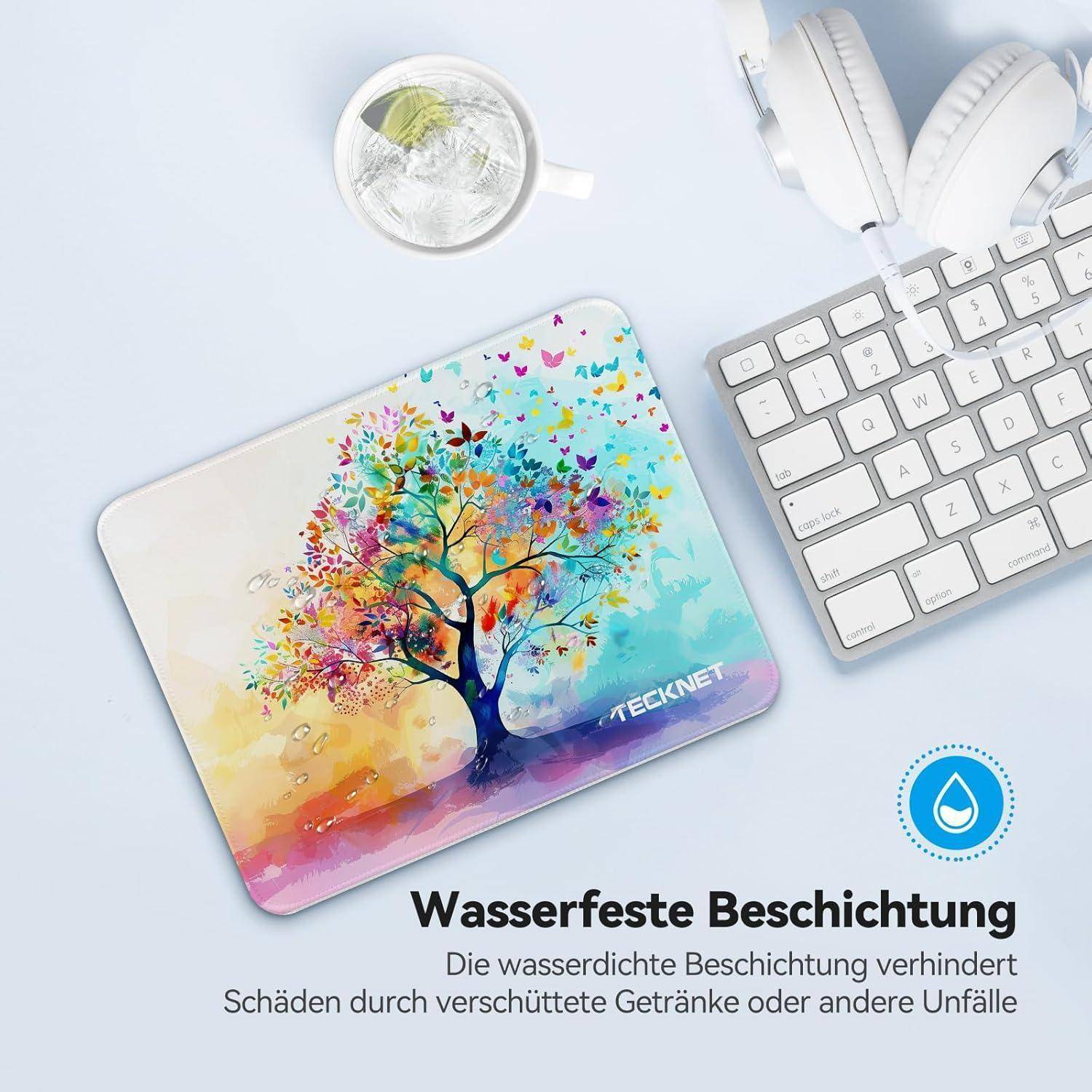 Ein buntes Mauspad mit Baumdesign, versehen mit wasserabweisender Beschichtung. Tastatur und Kopfhörer liegen daneben auf einer weißen Oberfläche.