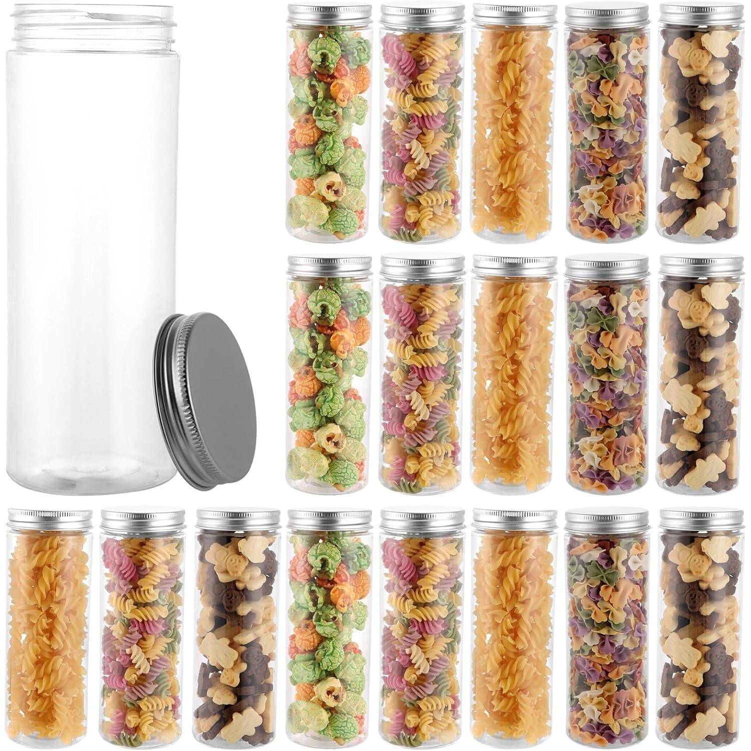 Set von 16 transparenten Kunststoff-Lebensmittelbehältern mit silbernen Deckeln, gefüllt mit bunter Pasta und Snacks; ein Behälter ist leer.