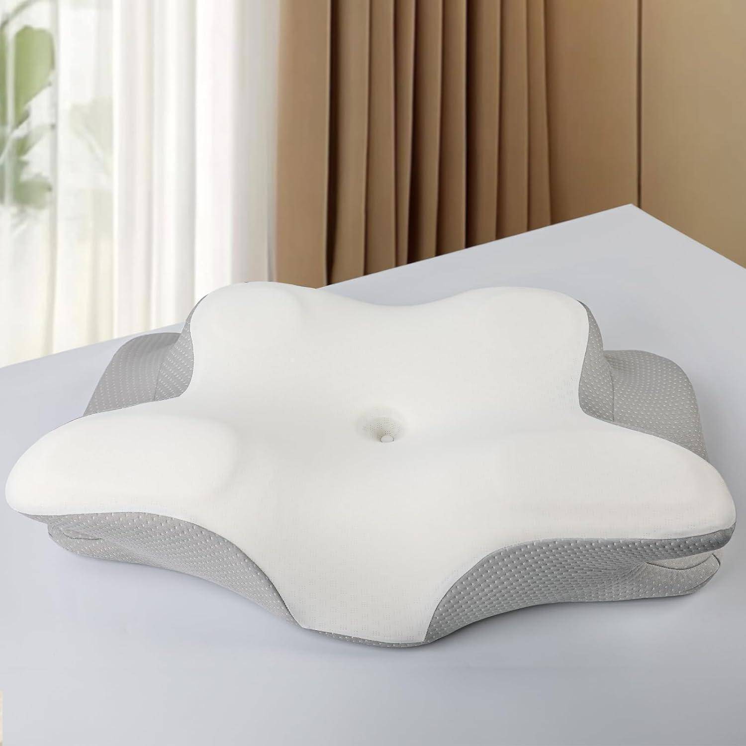 Weißes konturiertes Memoryschaum-Kissen mit grauen Seiten auf einem Tisch, entwickelt für ergonomische Nacken- und Kopfunterstützung, drinnen mit Vorhanghintergrund.