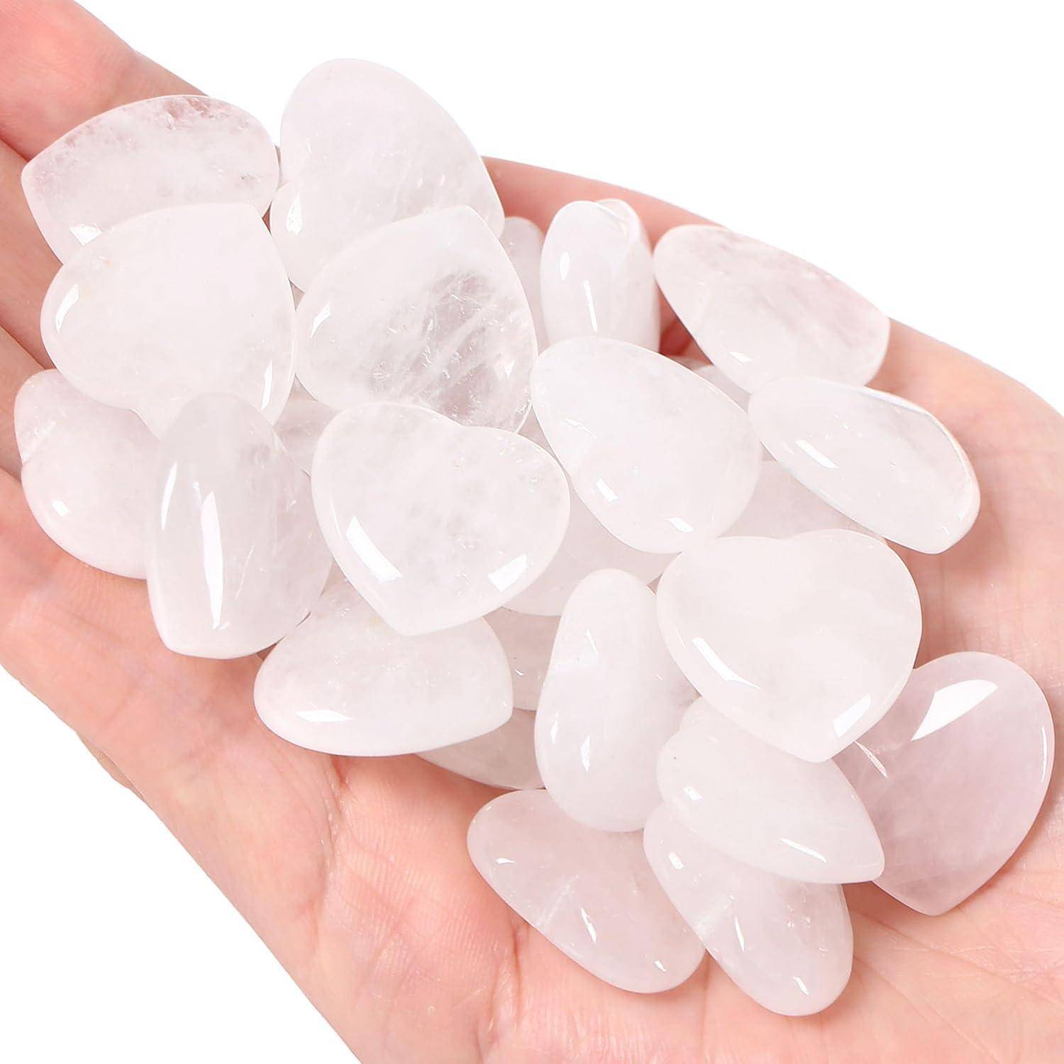 Eine Hand hält mehrere glatte, polierte Rosenquarzsteine in Herzform. Die Steine haben einen sanften rosafarbenen Ton und eine glänzende Oberfläche.