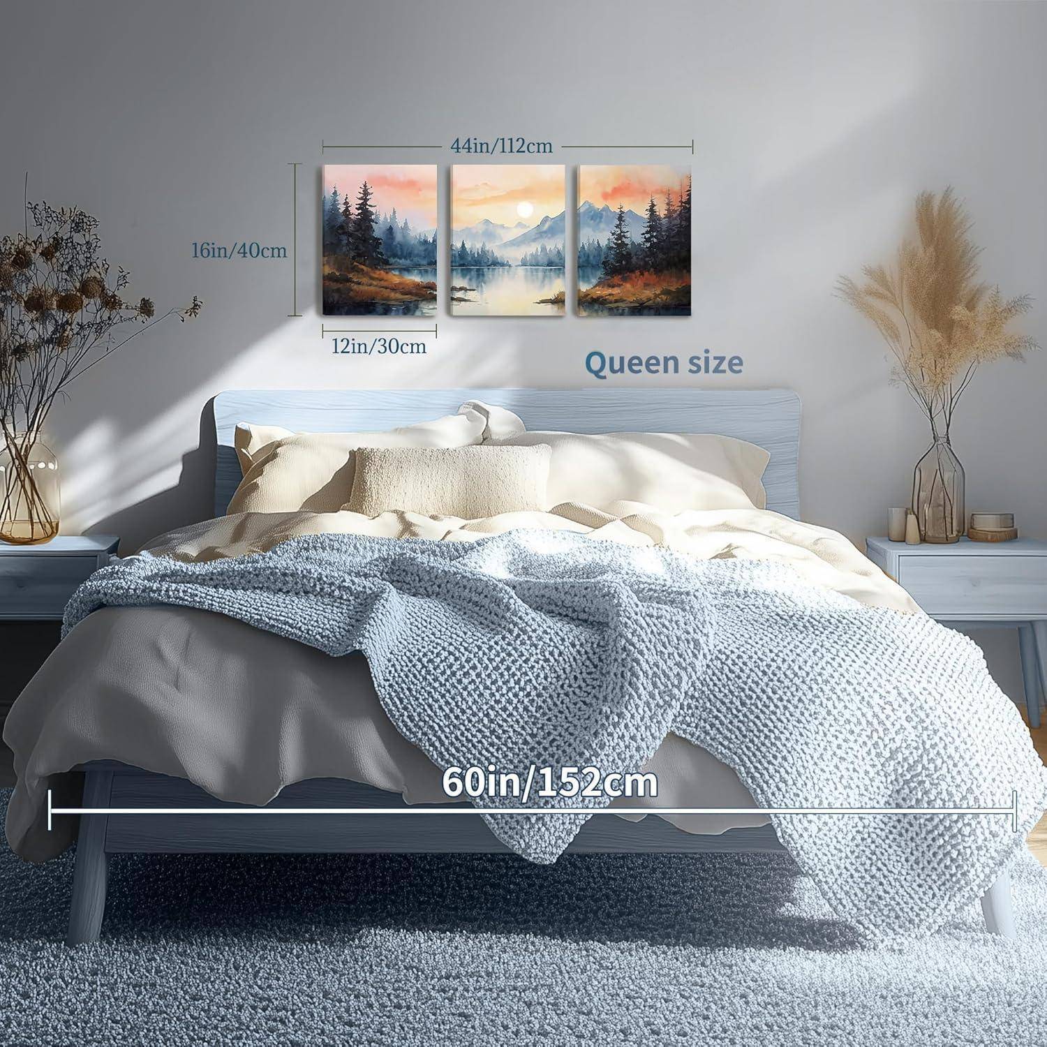 Ein gemütliches Schlafzimmer mit einem Doppelbett, das mit einer blauen gestrickten Decke bedeckt ist. Über dem Bett hängt ein dreiteiliges Landschaftsgemälde.
