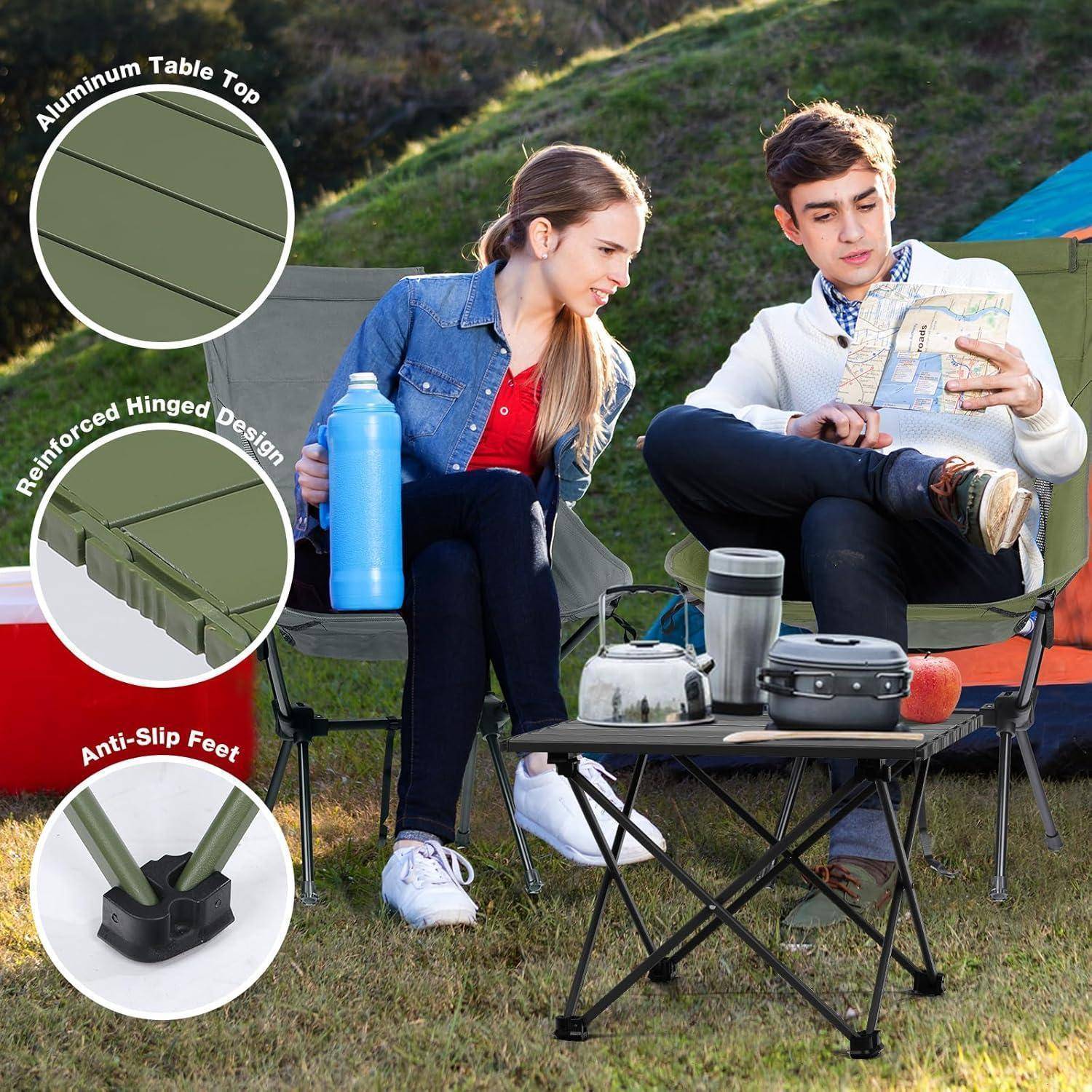 Eine Frau und ein Mann sitzen im Freien auf Campingstühlen und lesen eine Karte. In der Nähe steht ein tragbarer Tisch mit folgenden Merkmalen: Aluminium-Platte, Klappdesign, rutschfeste Füße.