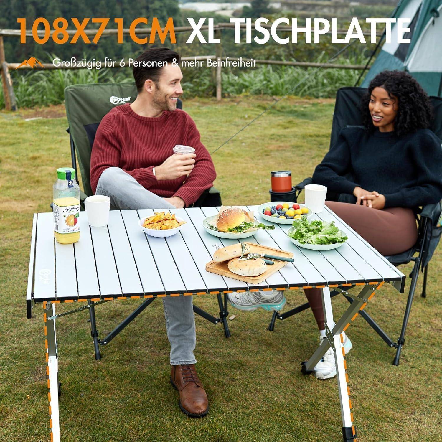 Ein Mann und eine Frau sitzen an einem Picknicktisch im Freien, teilen Getränke und Gebäck, mit einem Zelt im Hintergrund.