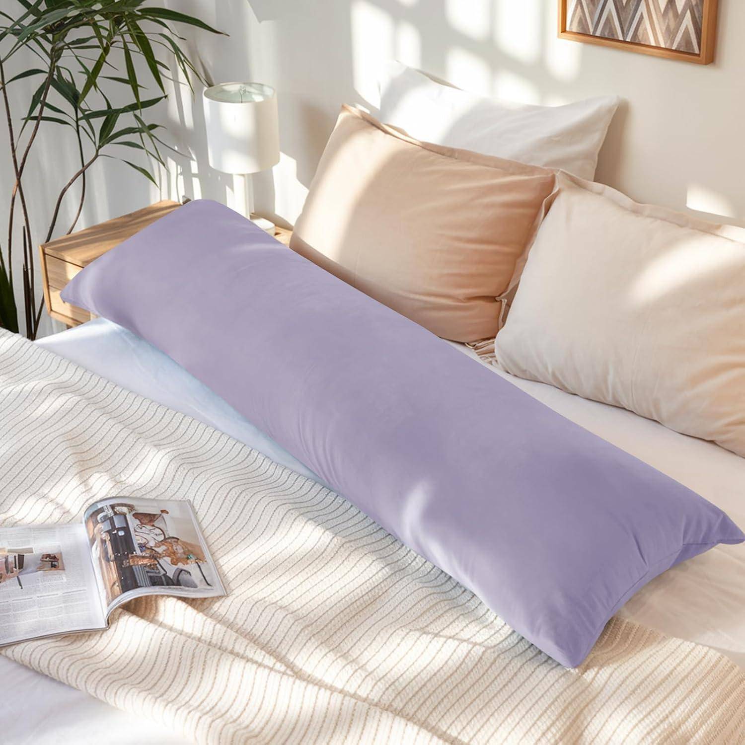 Ein sonnendurchflutetes Schlafzimmer zeigt ein ordentlich gemachtes Bett mit einem langen Lavendelkörperkissen, beigen Kissen und einer aufgeschlagenen Zeitschrift auf der weißen Bettdecke.