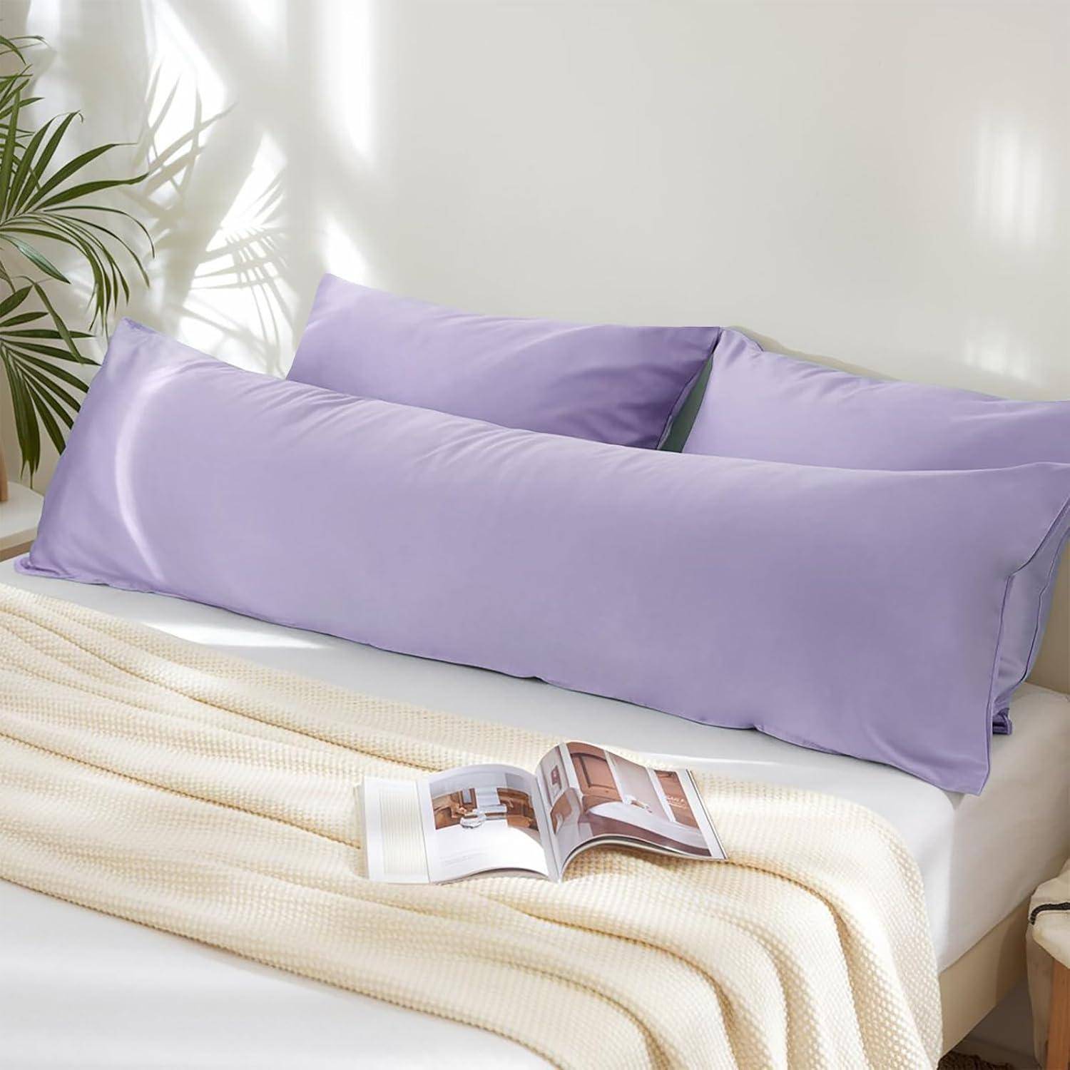 Ein hellviolettes Bodenkissen auf einem weißen Sofa mit einem geöffneten Buch auf Dekorseiten und einer Zimmerpflanze in der Nähe, alles in weichem, natürlichem Licht.