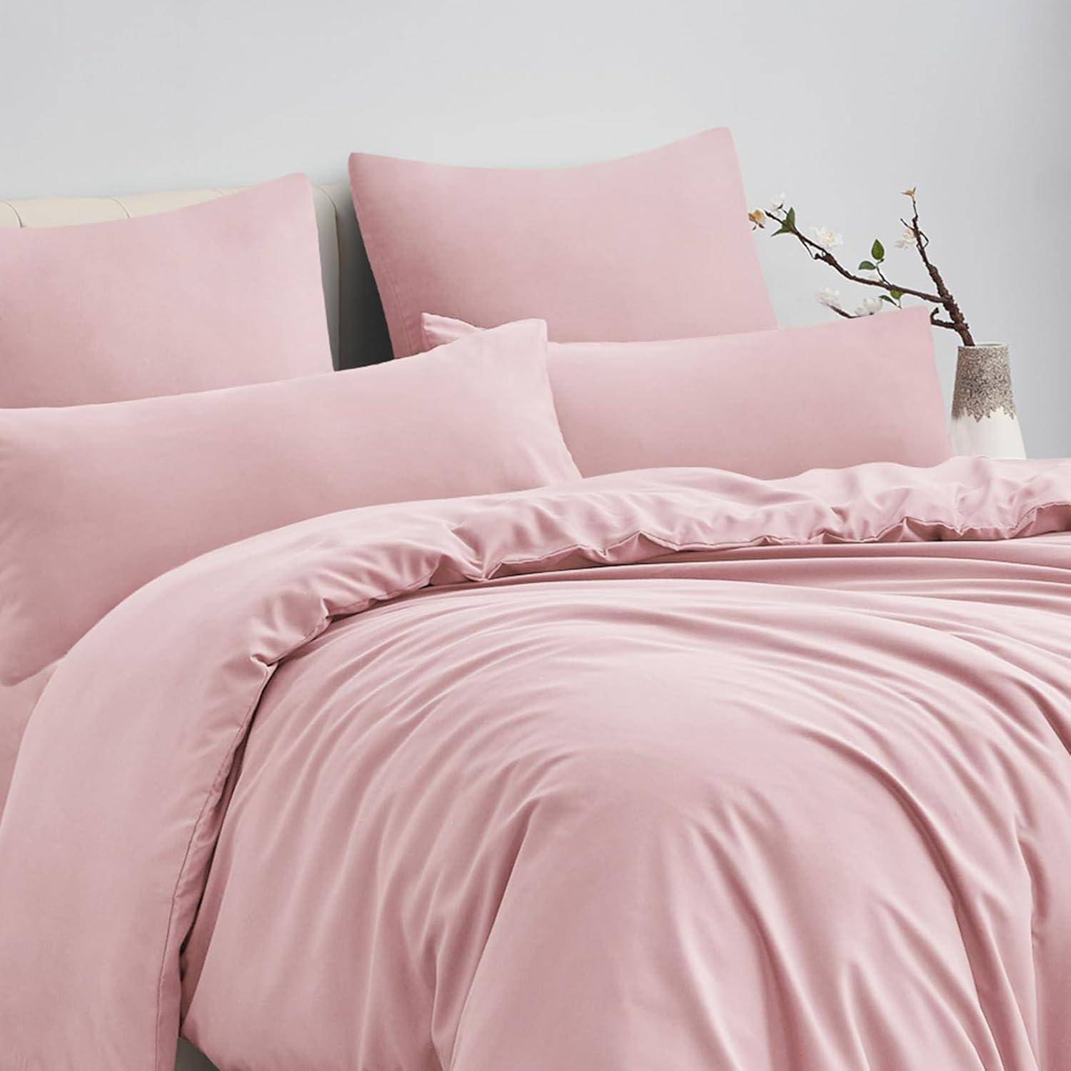 Ein ordentlich gemachtes Bett mit weicher rosa Bettwäsche, einschließlich Kissen, einer Bettdecke und einem dekorativ platzierten Zweig im Hintergrund.