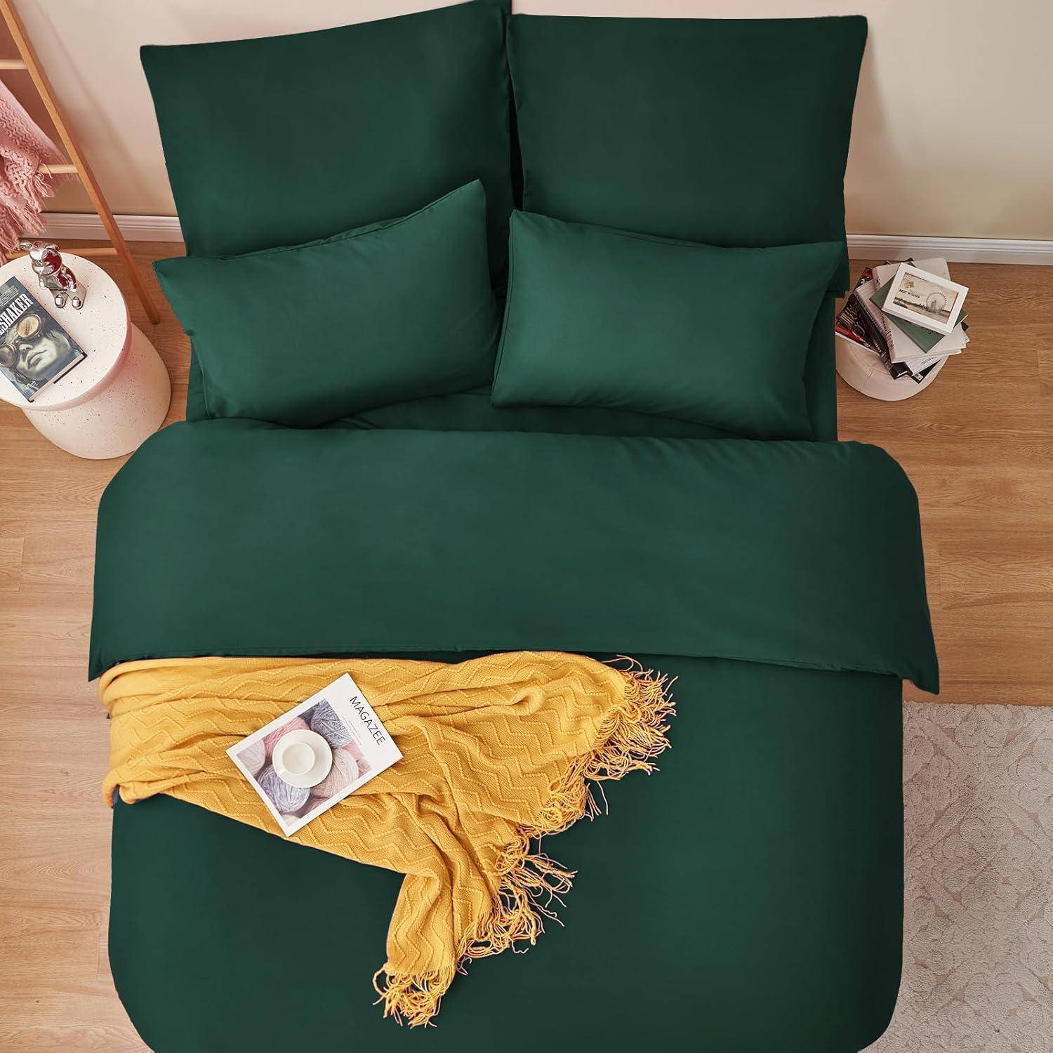 Ein ordentlich gemachtes Bett mit dunkelgrünen Laken und Kissen, einer goldgelben Decke und Zeitschriften obenauf, in einer gemütlichen Schlafzimmeratmosphäre.