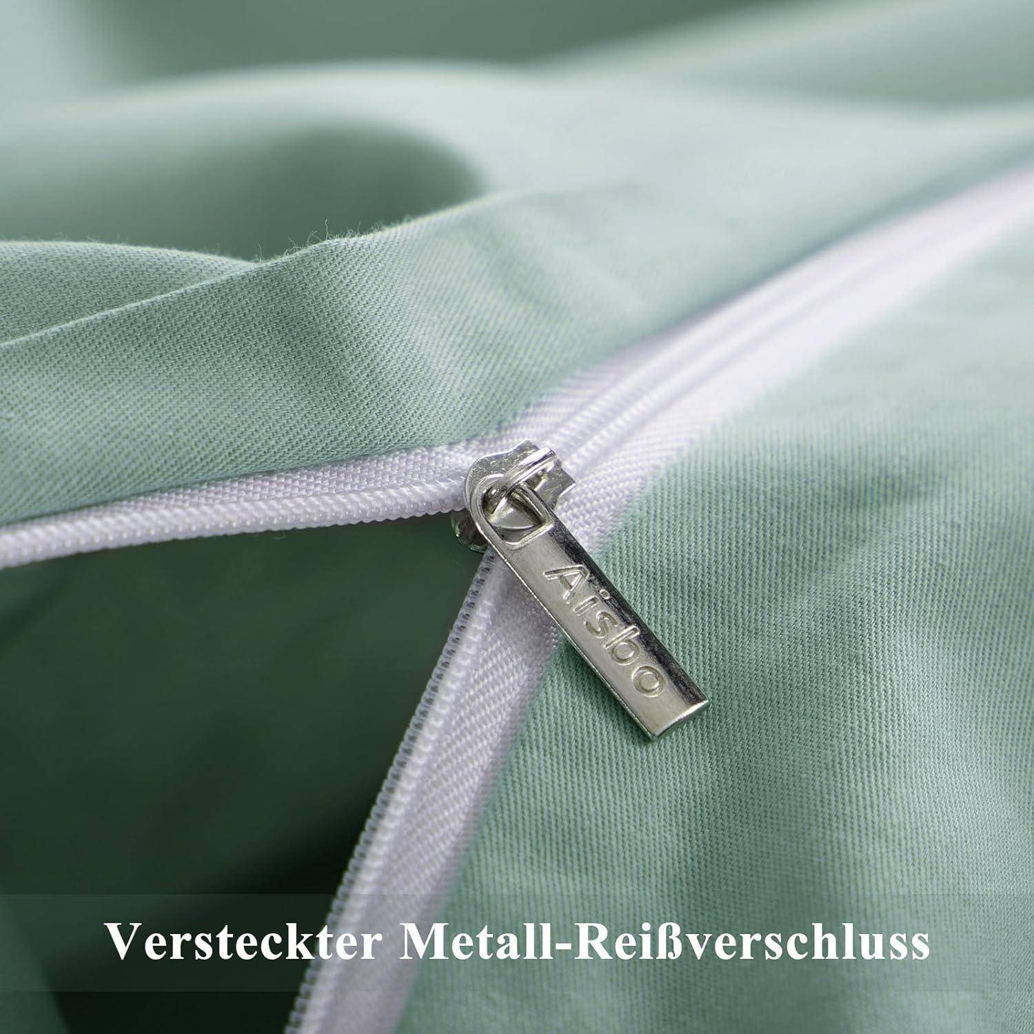 Eine Nahaufnahme eines grünen Stoffes mit einem weißen versteckten Metall-Reißverschluss. Das Wort 'Alisbo' ist auf dem Reißverschluss-Zuggriff eingraviert. Der deutsche Text darunter lautet 'Versteckter Metall-Reißverschluss'.