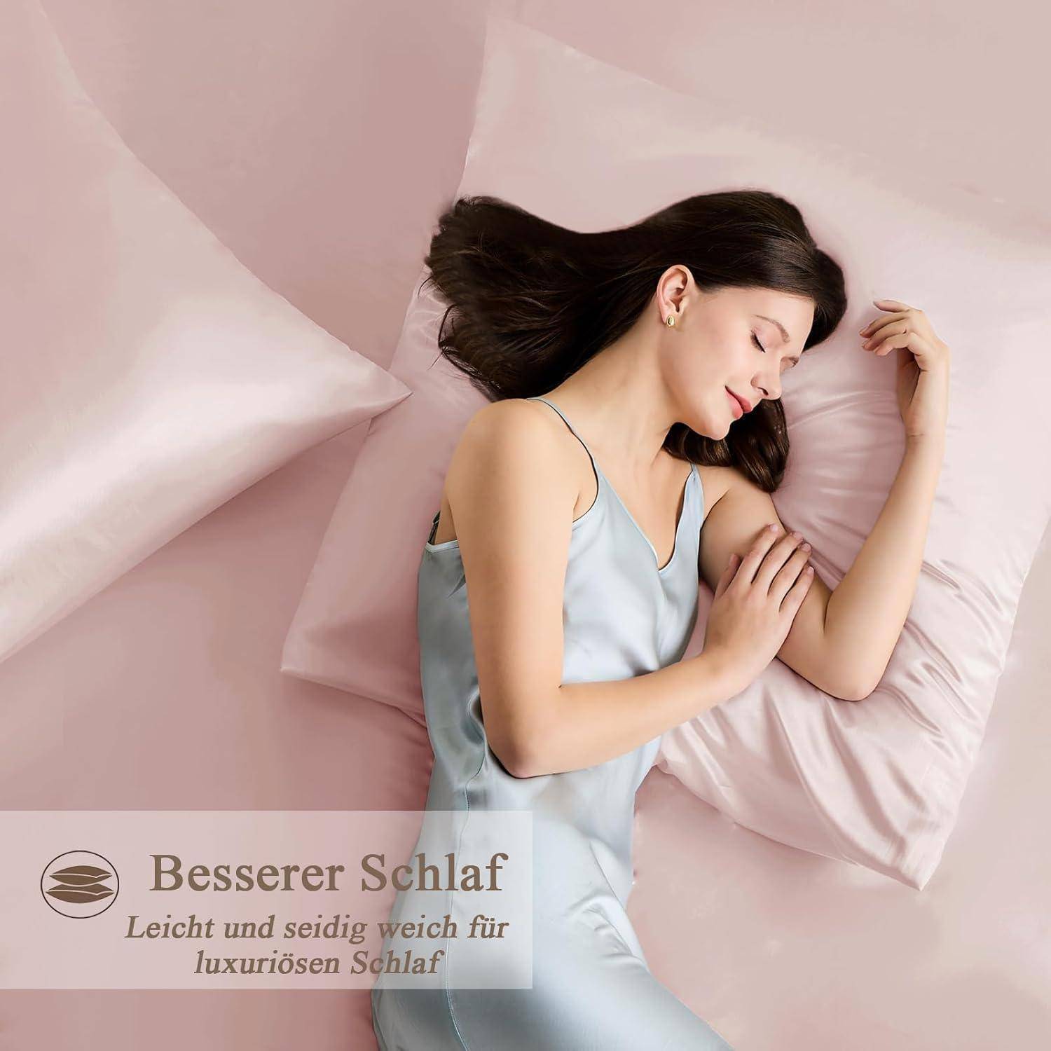 Eine Frau schläft friedlich auf pinkfarbener Satin-Bettwäsche. Deutscher Text liest sich: 'Besserer Schlaf', 'Leicht und seidig weich für luxuriöses Wohlfühl'.