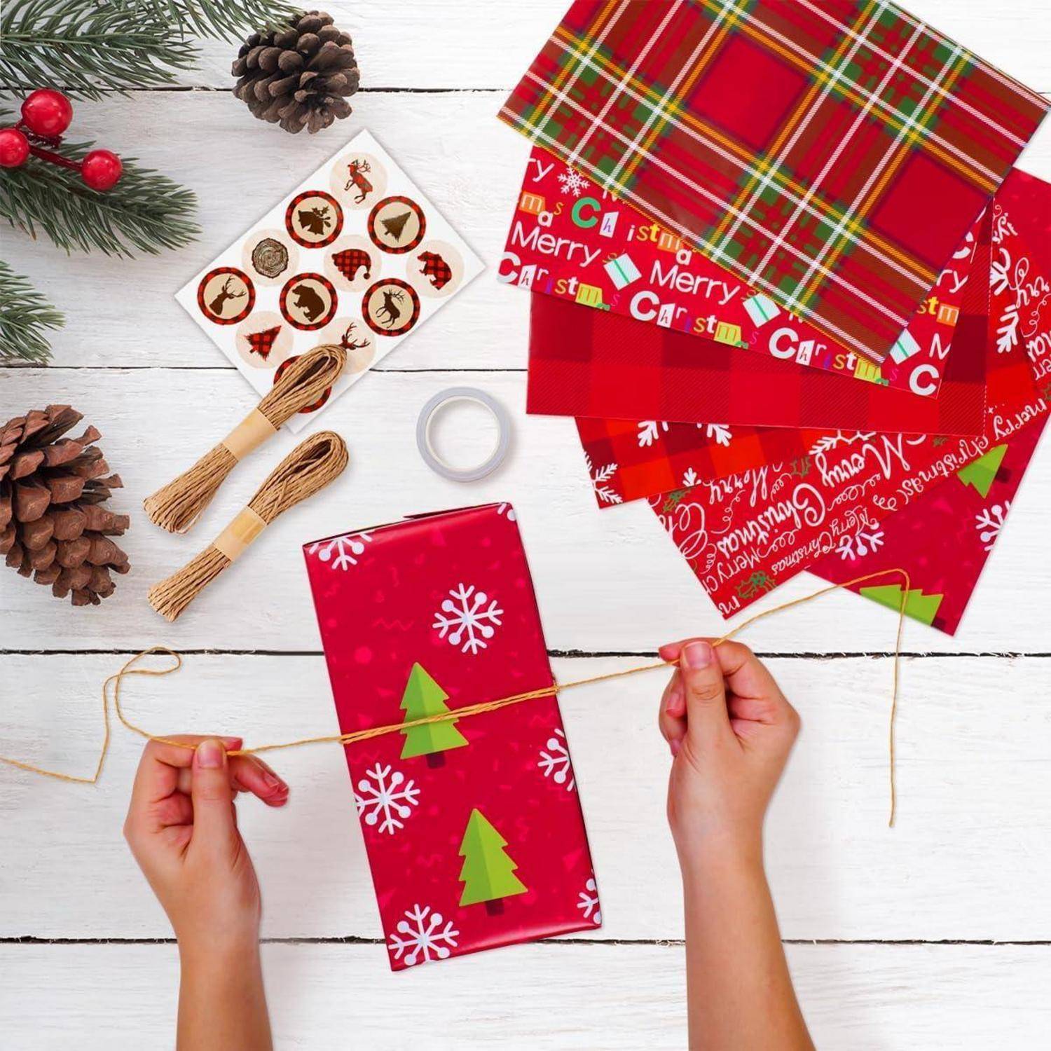 Weihnachtsgeschenke einpacken mit rotem und grünem Papier, Band und Dekorationen. Hände, die Bindfaden um ein eingepacktes Geschenk binden.
