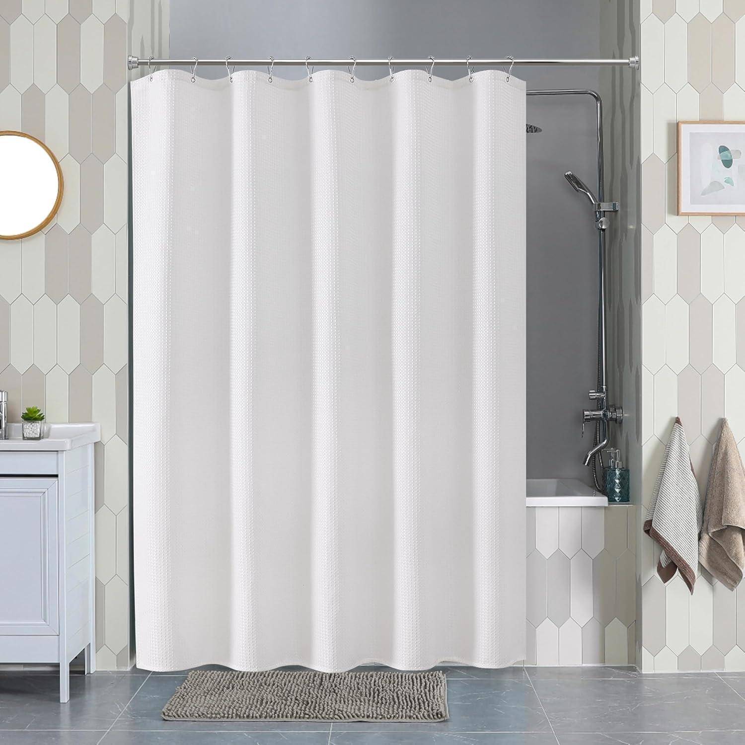 Badezimmer mit sechseckigen Wandfliesen, weißem Duschvorhang über einer Badewanne, einem Waschtisch mit rundem Spiegel und hängenden Handtüchern.