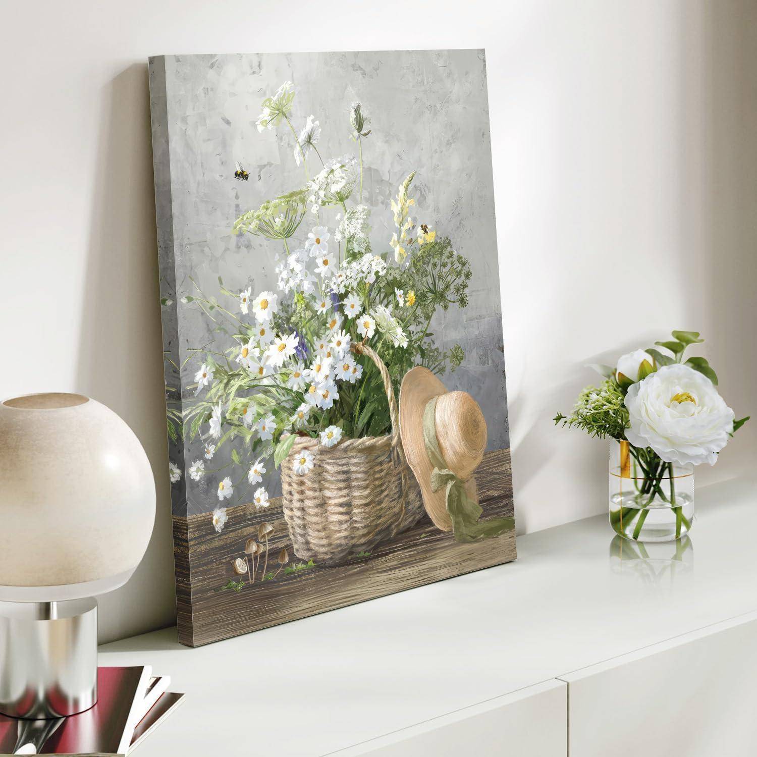 Eine Leinwand auf einem Regal zeigt einen Korb mit Gänseblümchen, neben dem ein Strohhut liegt. Eine nahegelegene Vase enthält passende Gänseblümchen.