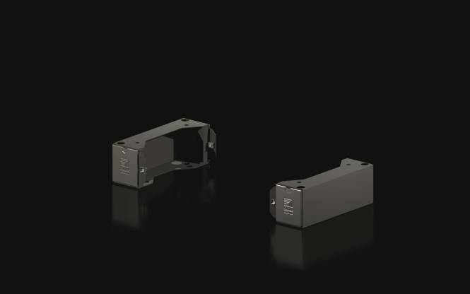 Zwei dunkle, kantige Metallhalterungen auf einer schwarzen reflektierenden Oberfläche.