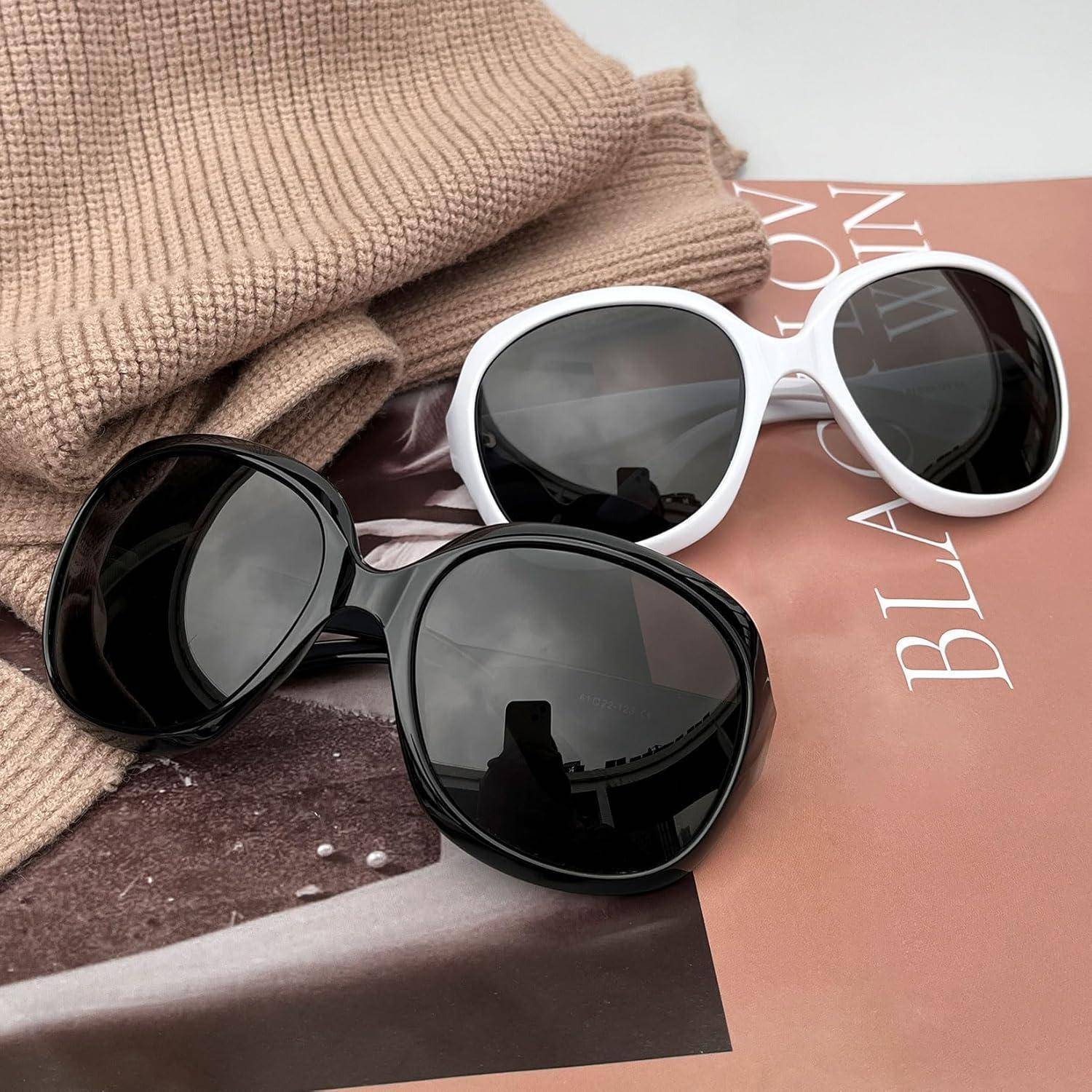 Schwarze und weiße Sonnenbrille, die auf einem braunen Hut liegen, über einer Zeitschrift platziert.