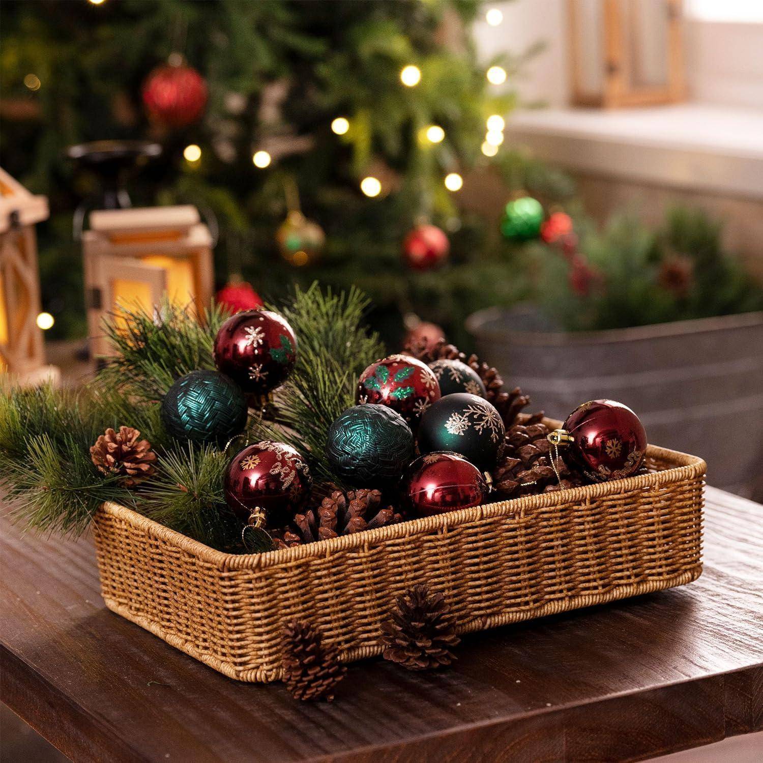 Ein geflochtener Korb, gefüllt mit Tannenzweigen, Zapfen und roten sowie türkisfarbenen Weihnachtsschmuck, steht auf einem Holztisch, umgeben von festlicher Dekoration.